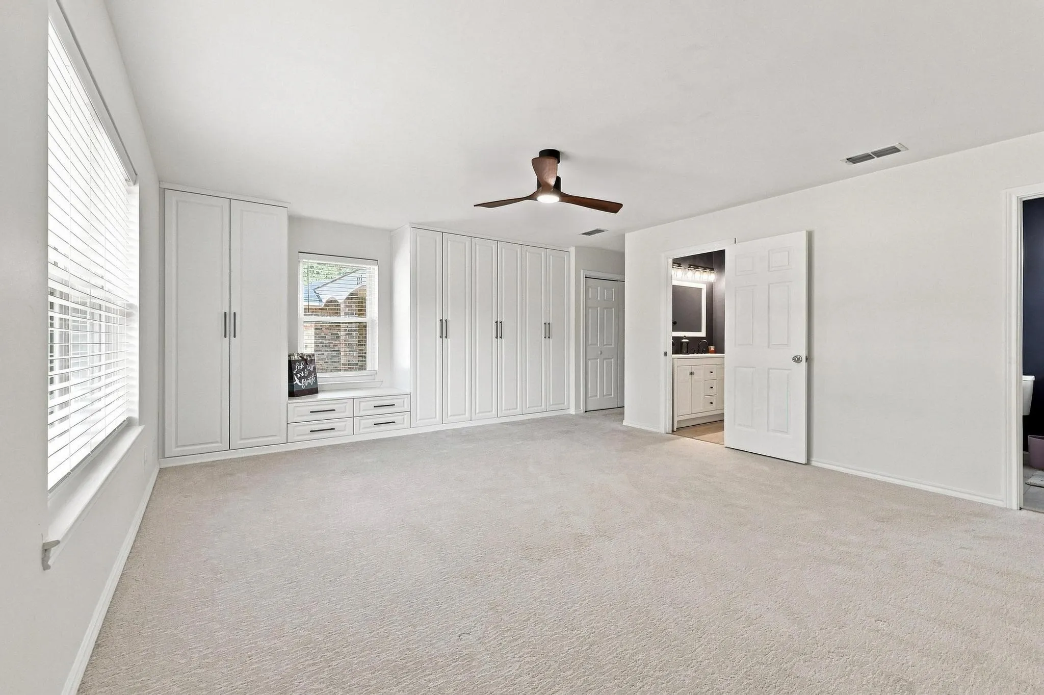 Wall-to-wall custom closet system offering lots of storage with carpeting and neutral paint throughout