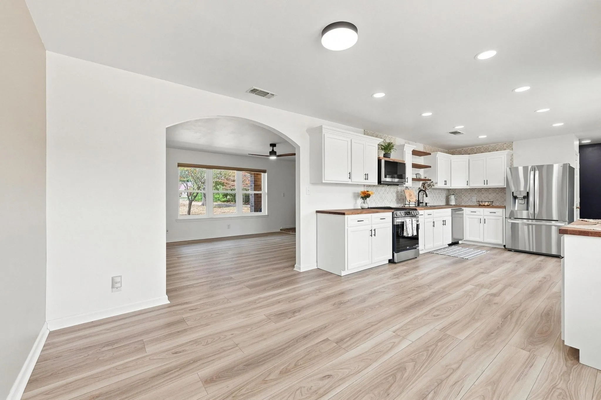 Kitchen featuring white cabinetry, wood-finish countertops, stainless steel appliances, and a tiled backsplash