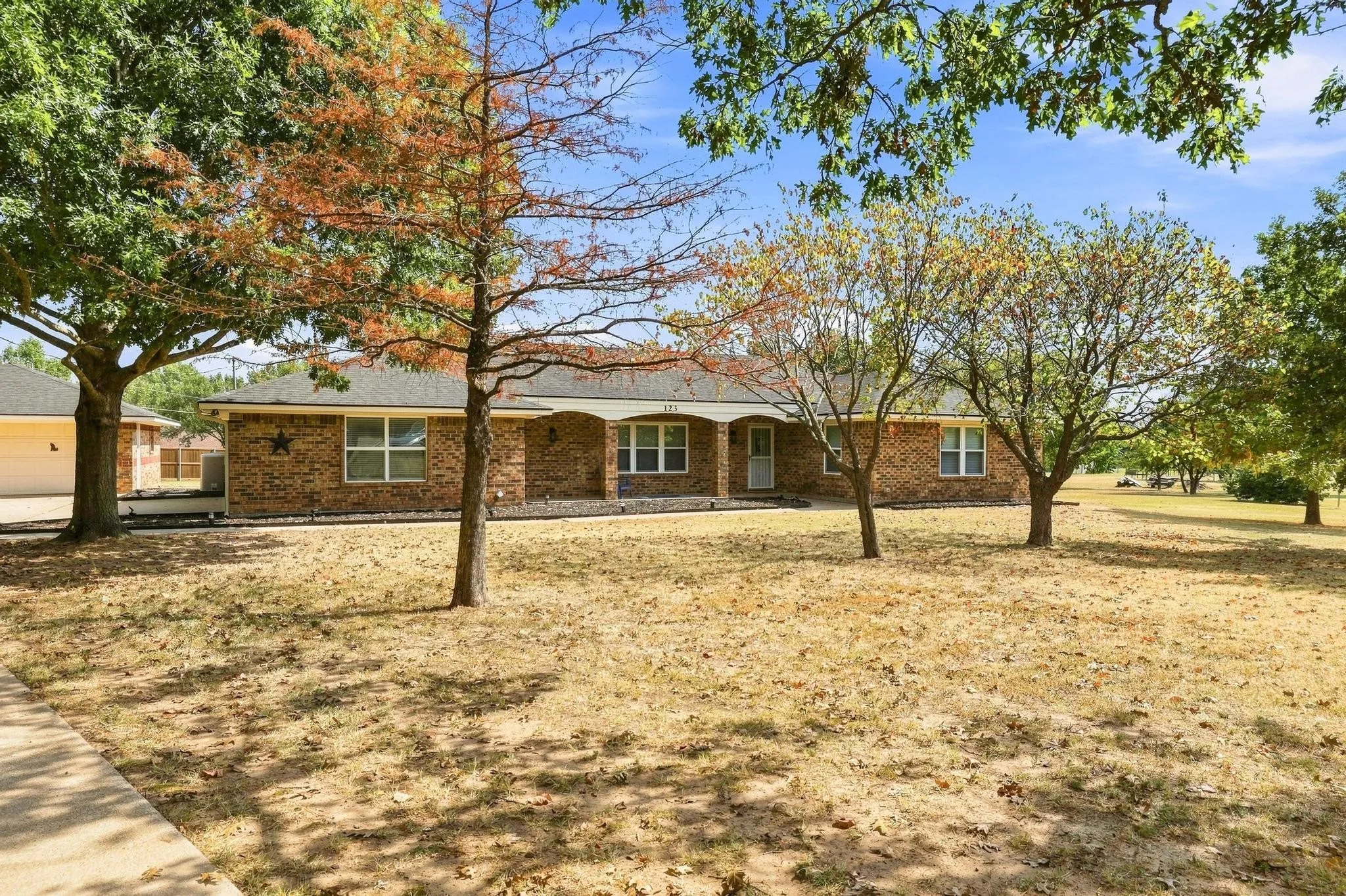 Brick ranch home situated on expansive grounds with mature shade trees and open lawn