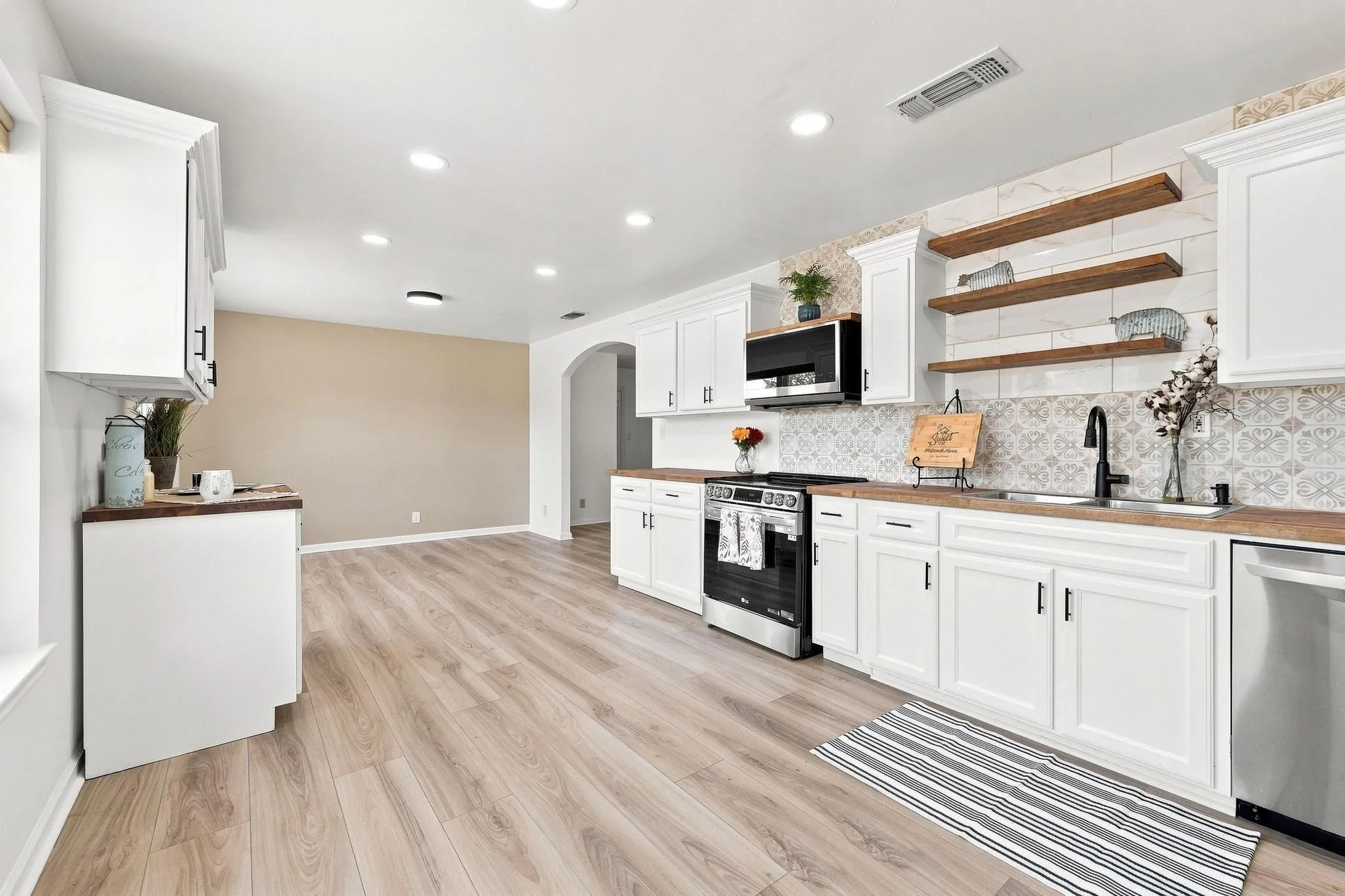 Kitchen featuring new white cabinetry, wood-finish countertops, stainless steel appliances, and wood-finish flooring
