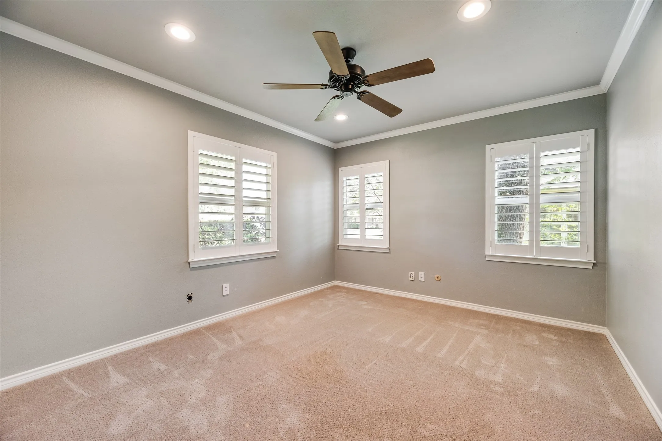 Unfurnished room with a ceiling fan, crown molding, plenty of natural light, light colored carpet, and recessed lighting