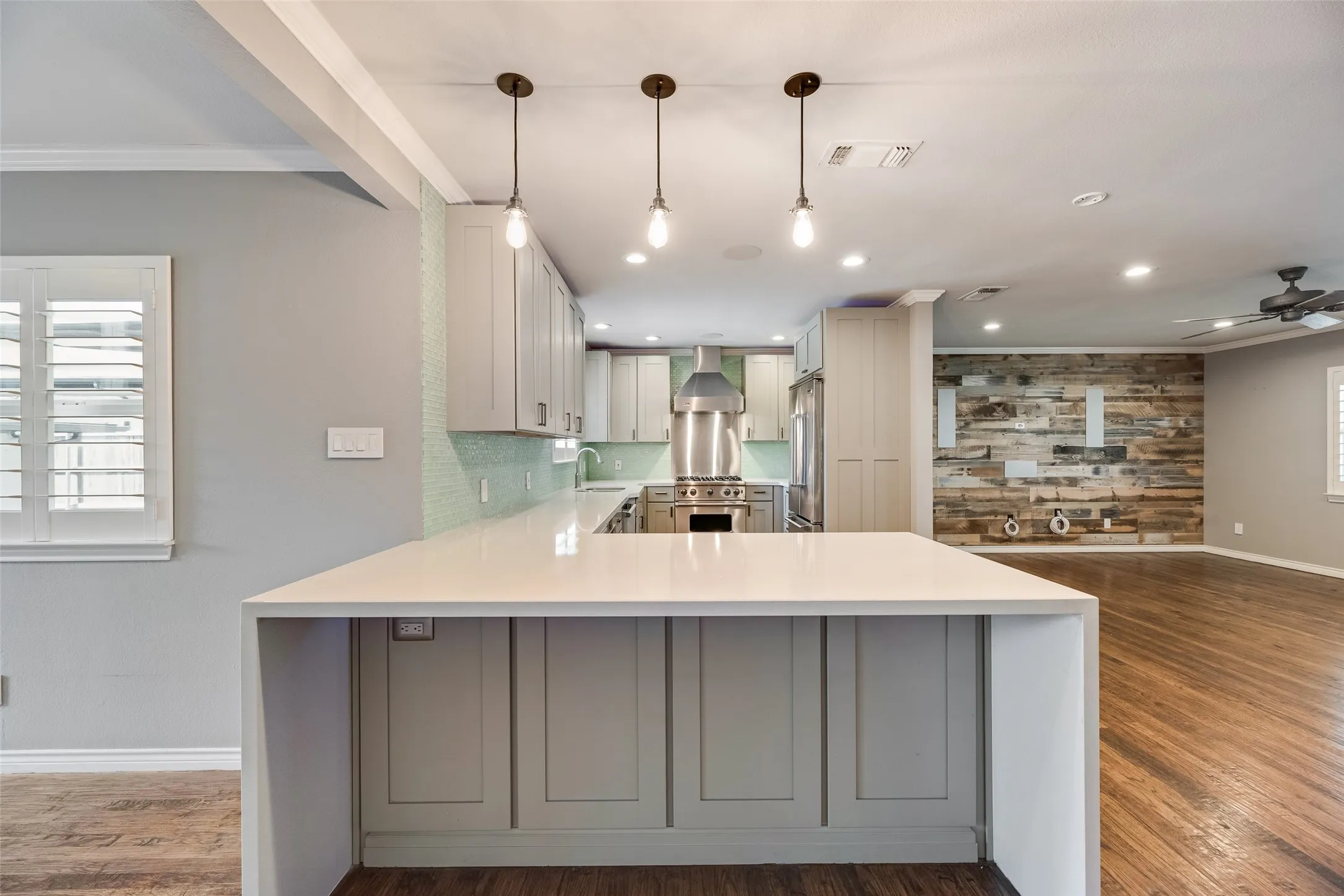 Kitchen featuring light stone counters, dark wood-type flooring, a peninsula, and crown molding