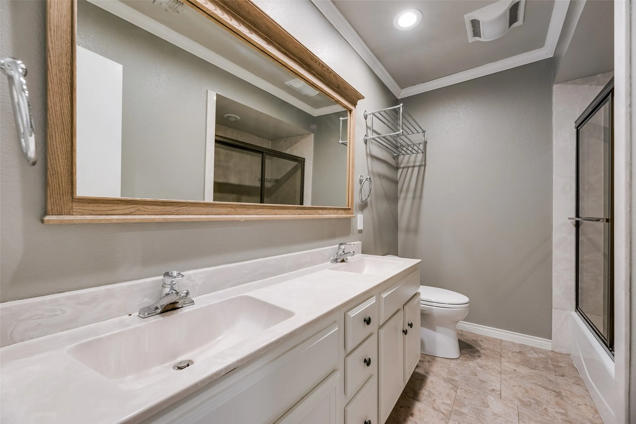 Bathroom featuring ornamental molding, double vanity, combined bath / shower with glass door, and recessed lighting