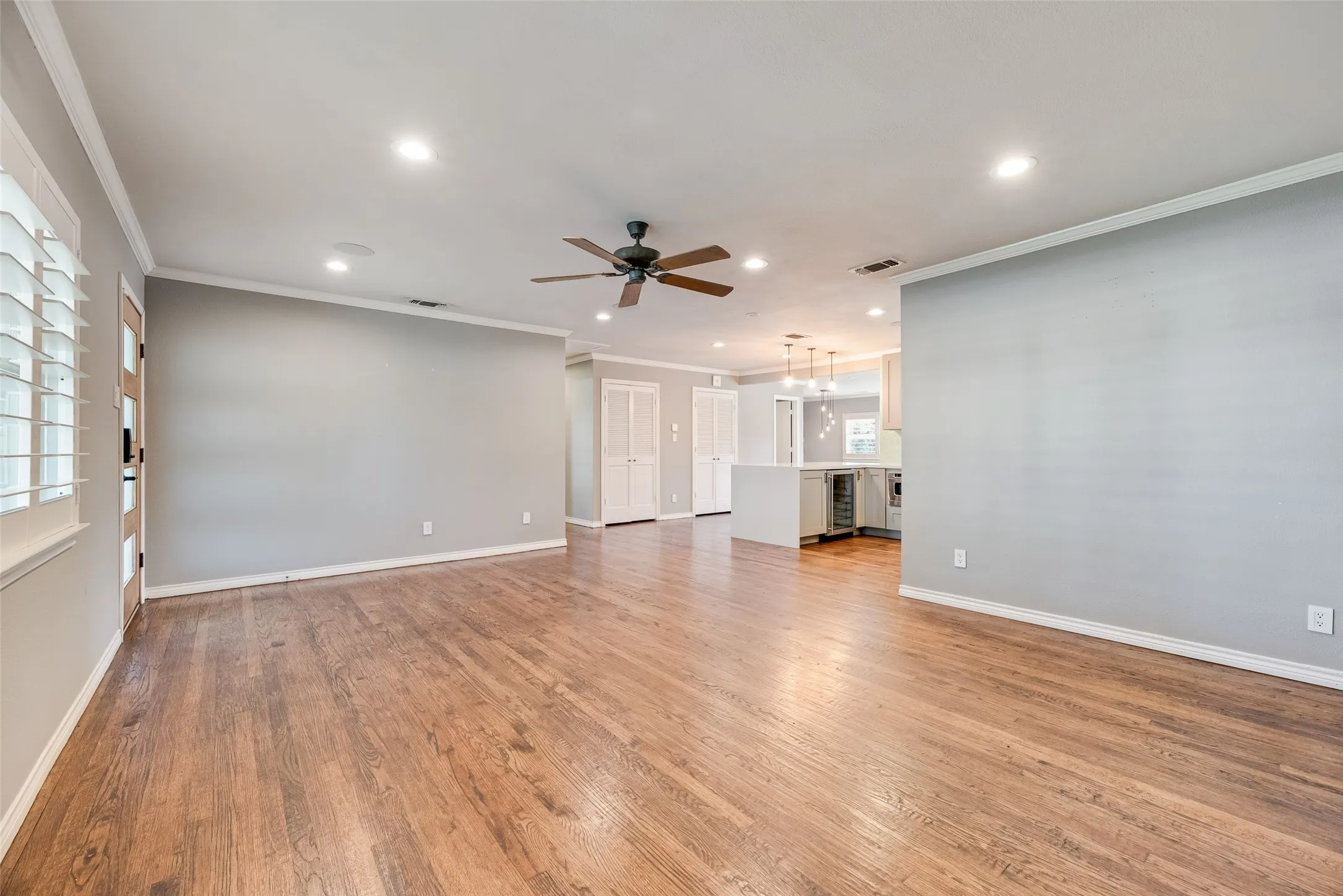 Unfurnished living room featuring ornamental molding, a ceiling fan, light wood finished floors, beverage cooler, and recessed lighting