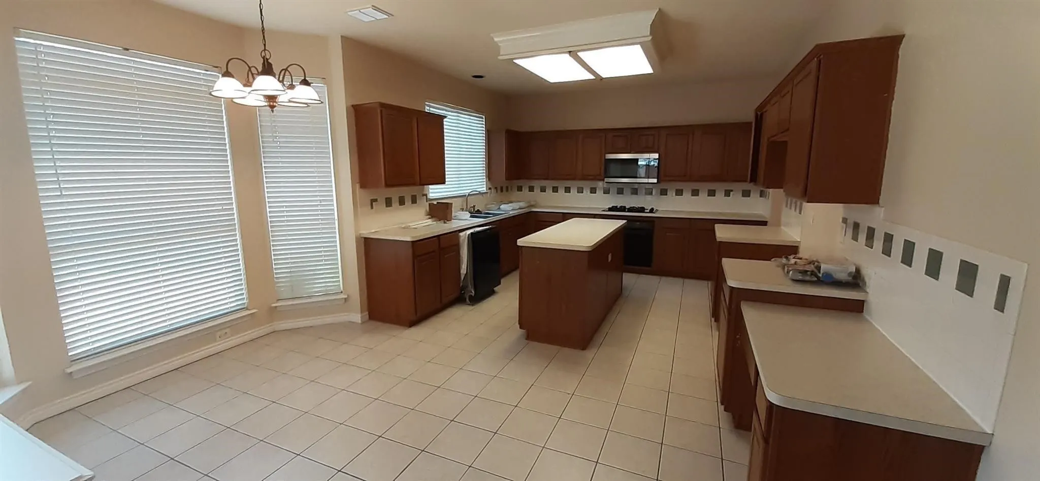 Kitchen featuring a center island, extensive cabinetry, light-toned countertops, tile flooring, and integrated stainless steel appliances