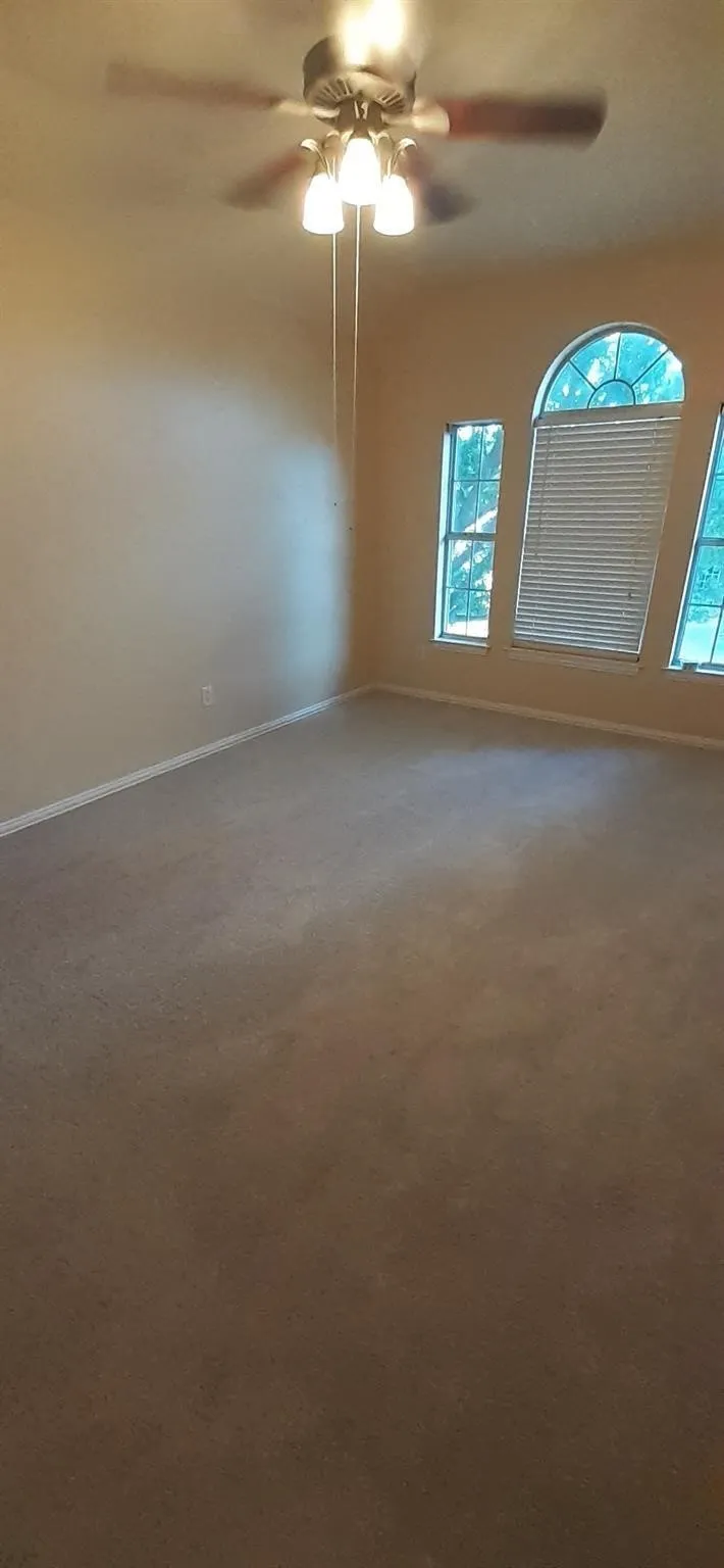 Carpeted flooring with a neutral finish, vaulted ceiling, and an arched window with horizontal blinds