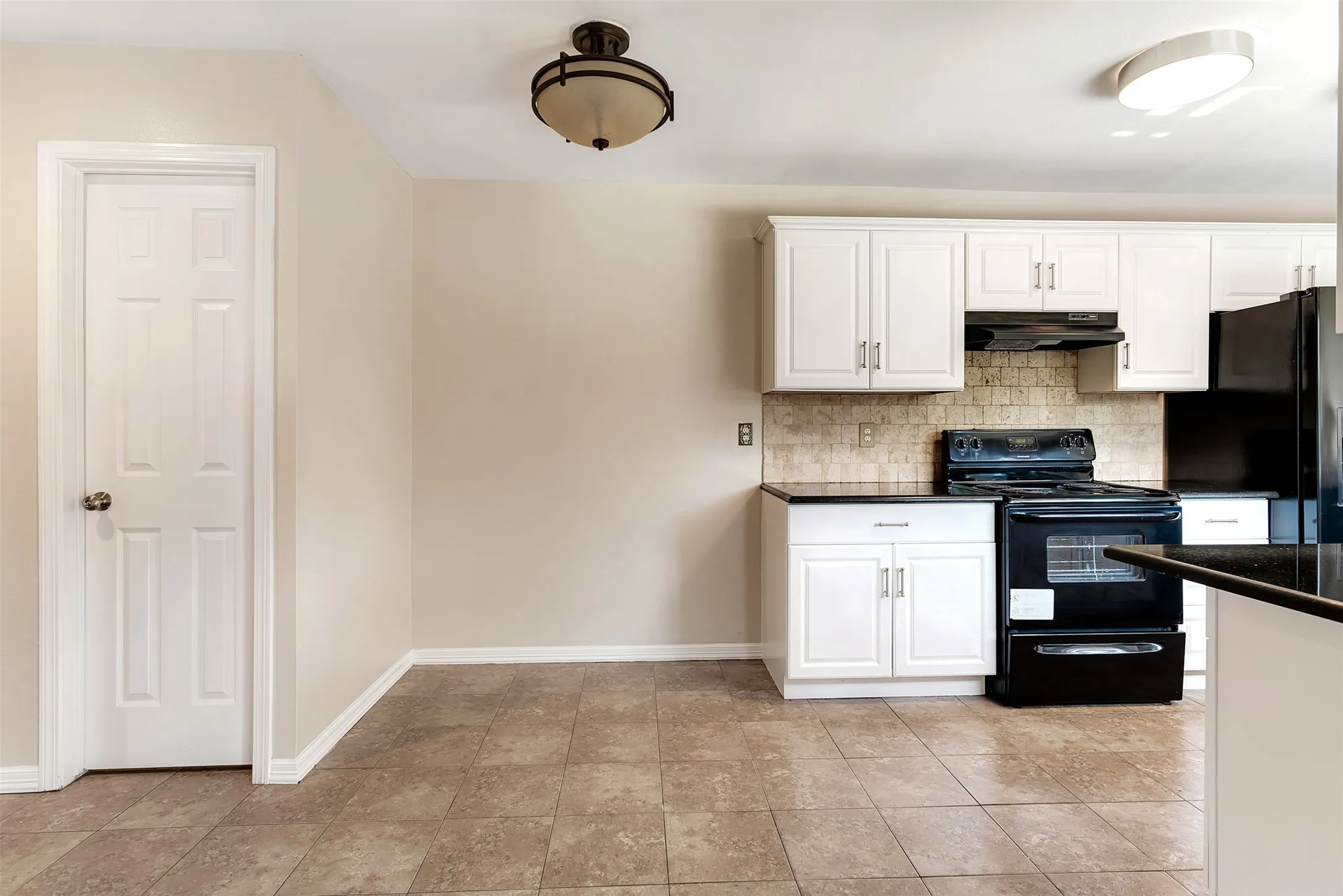 Kitchen featuring white cabinetry, black appliances, dark countertops, and a tiled backsplash