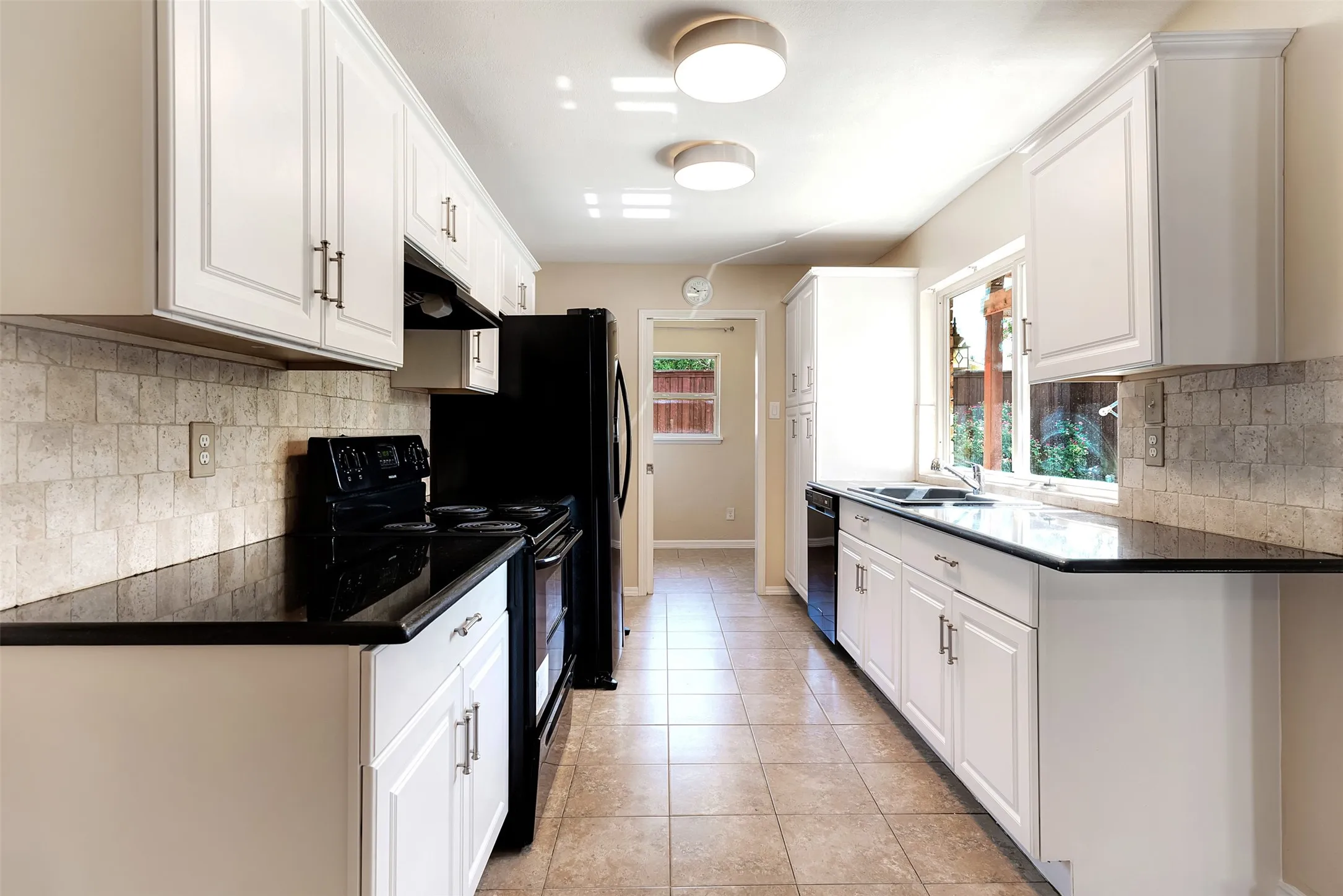 Galley kitchen featuring white cabinetry, dark countertops, tiled flooring, and a tiled backsplash