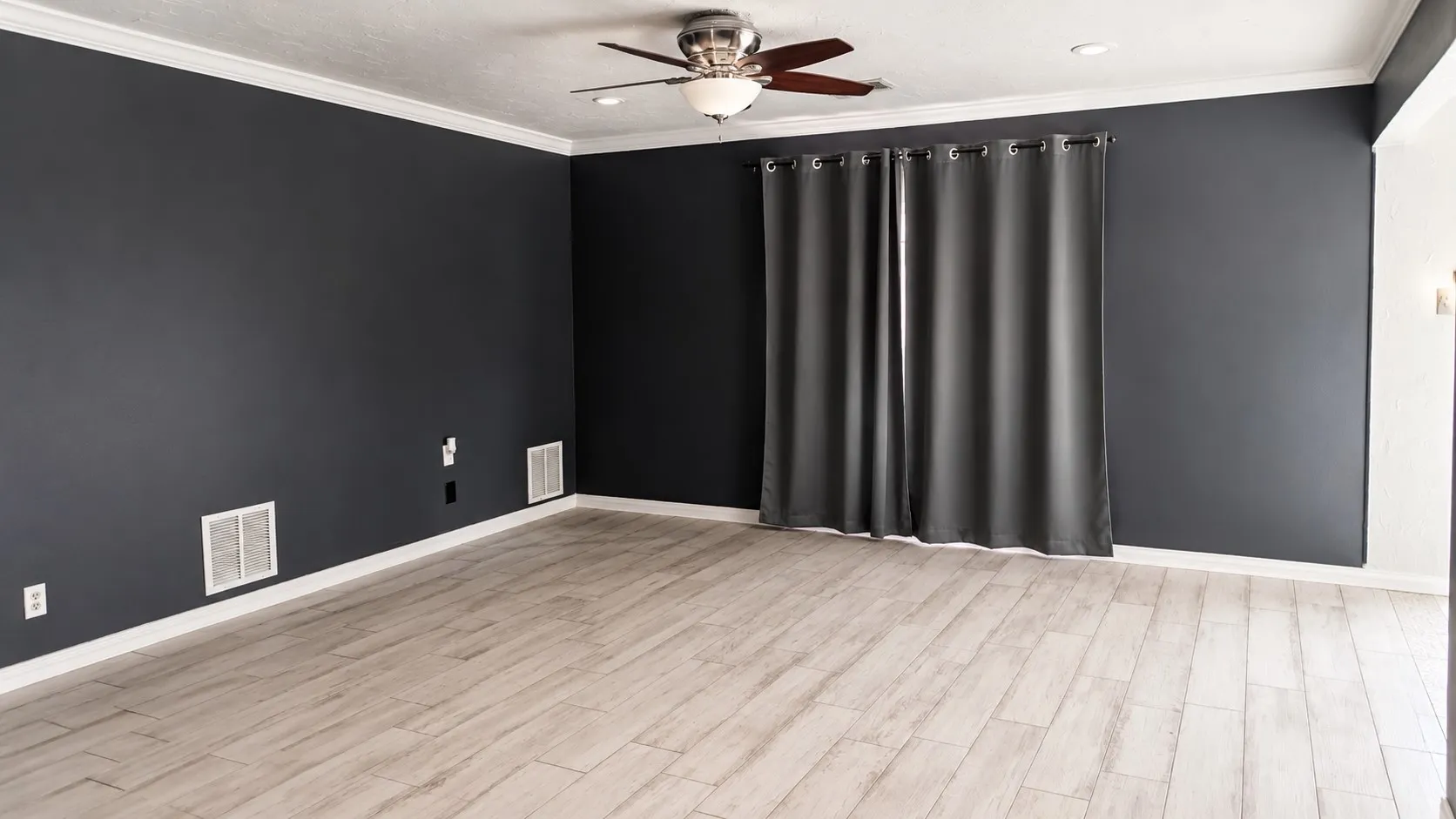 Wood-finish flooring, dark accent walls, white crown molding, recessed lighting, and a ceiling fan with integrated lighting