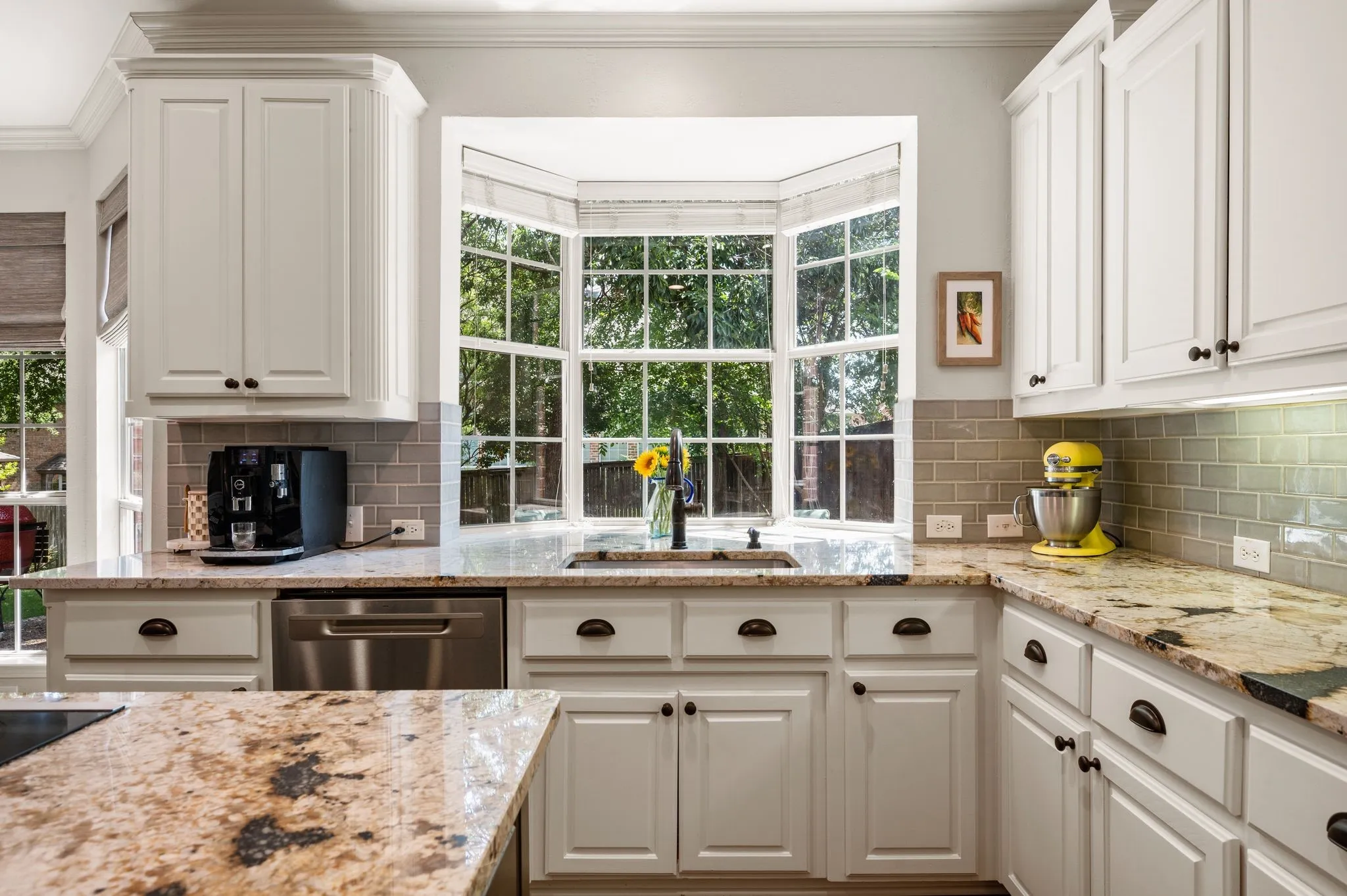 The kitchen sink is positioned beneath a beautiful bay window, bringing natural light & peaceful backyard views into the space.