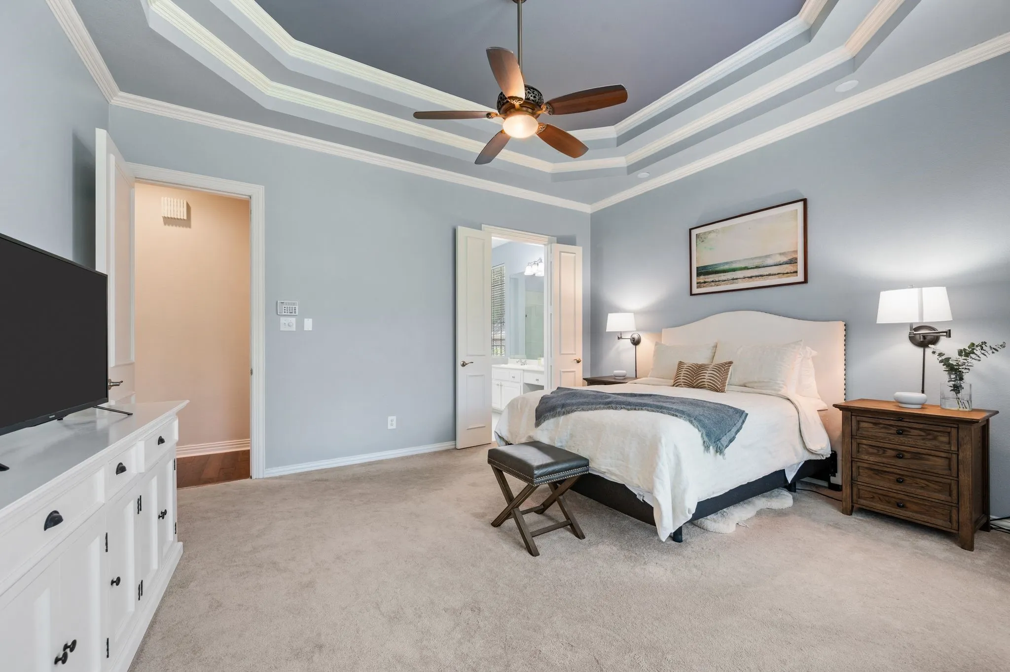 Spacious owner’s suite features plush carpet, private bath access & an impressive tiered tray ceiling with detailed molding.