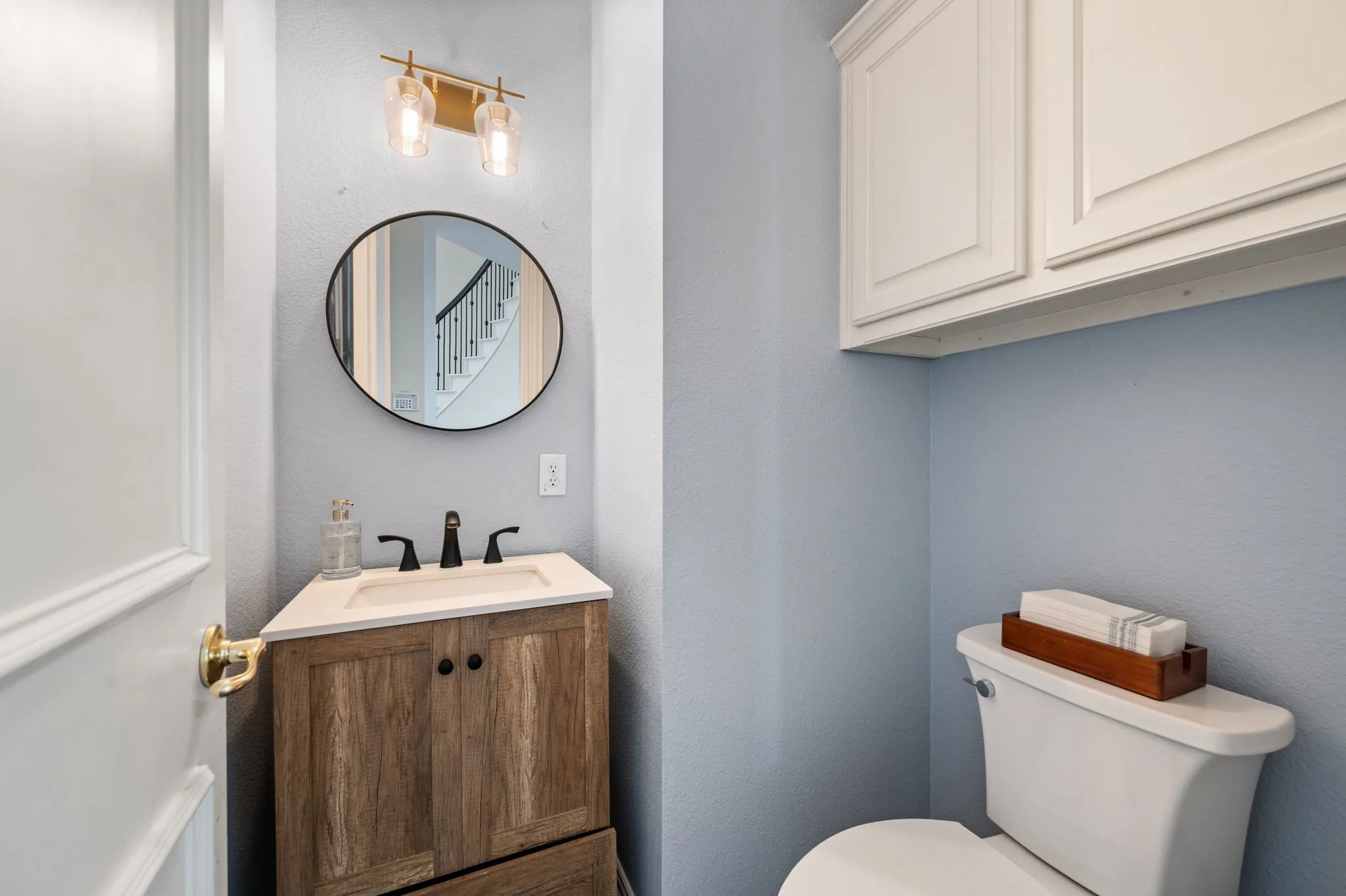 Updated powder bath features a modern vanity, matte black fixtures, stylish lighting & additional upper storage.