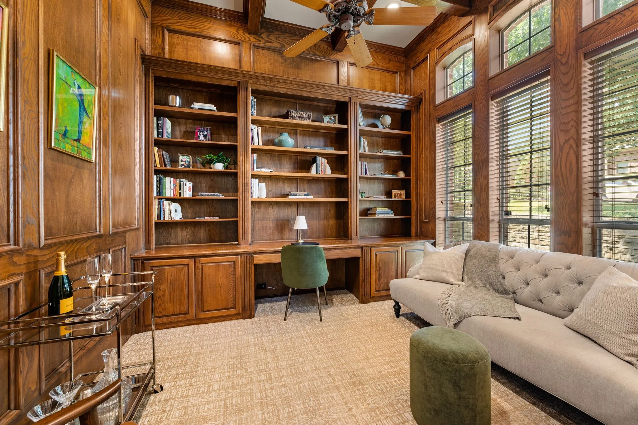 Handsome wood-paneled study features extensive built-in shelving, a dedicated workspace & tall windows overlooking the front yard.