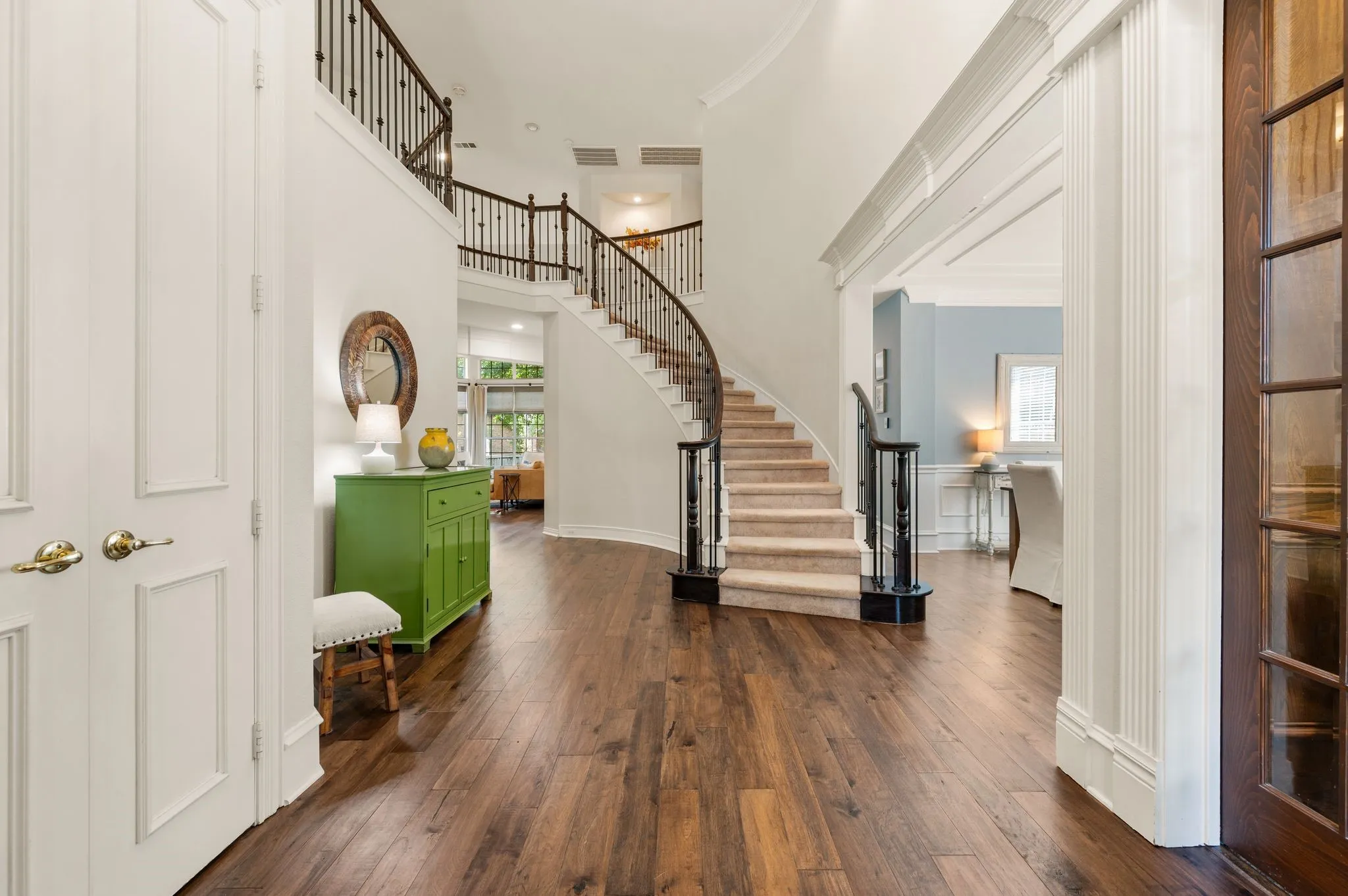 A grand two-story foyer makes a memorable first impression with rich wood flooring, detailed trim & an elegant curved staircase.