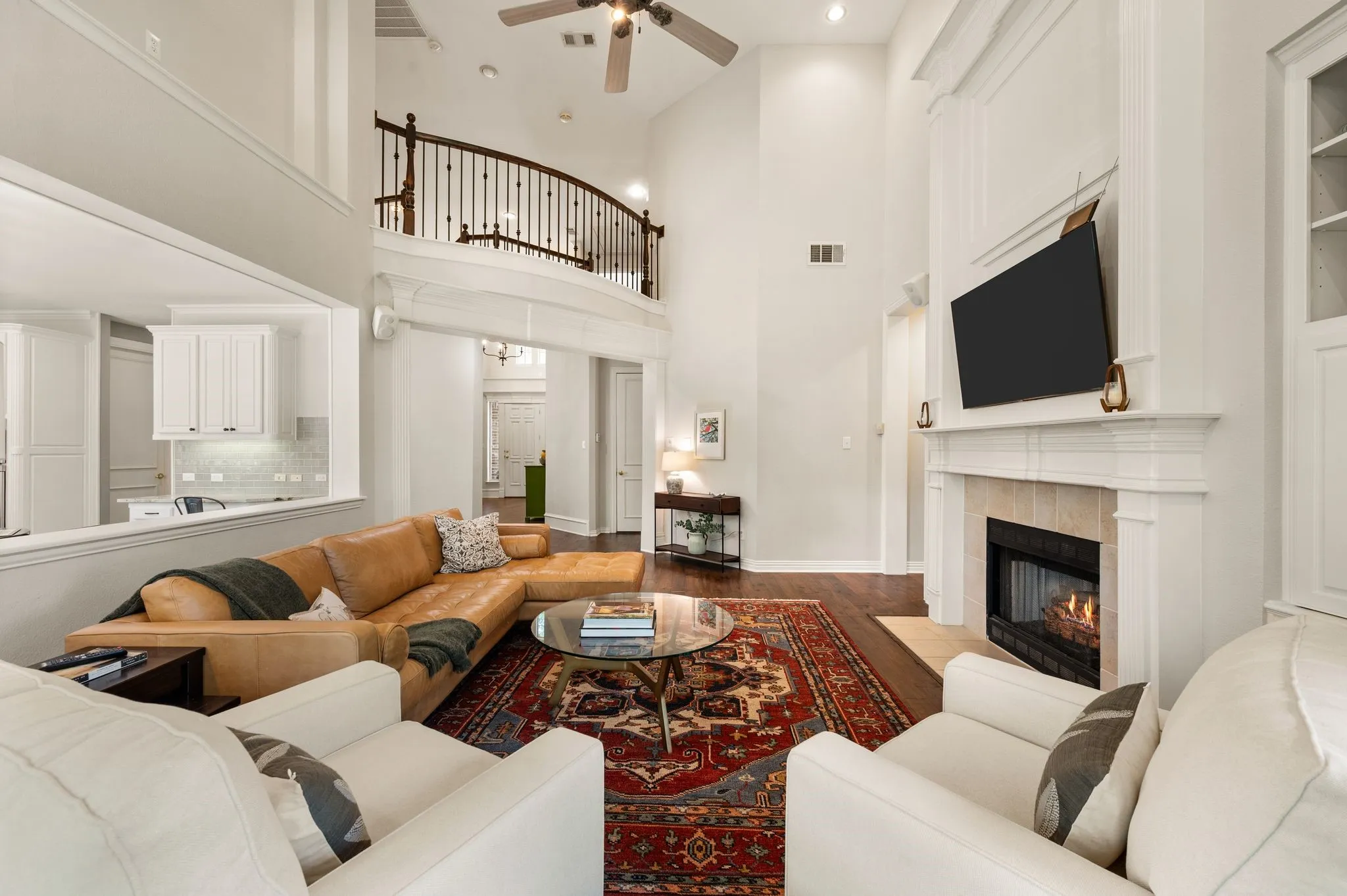 Another view showcases the family room’s impressive ceiling height, open staircase, fireplace & flexible seating space.