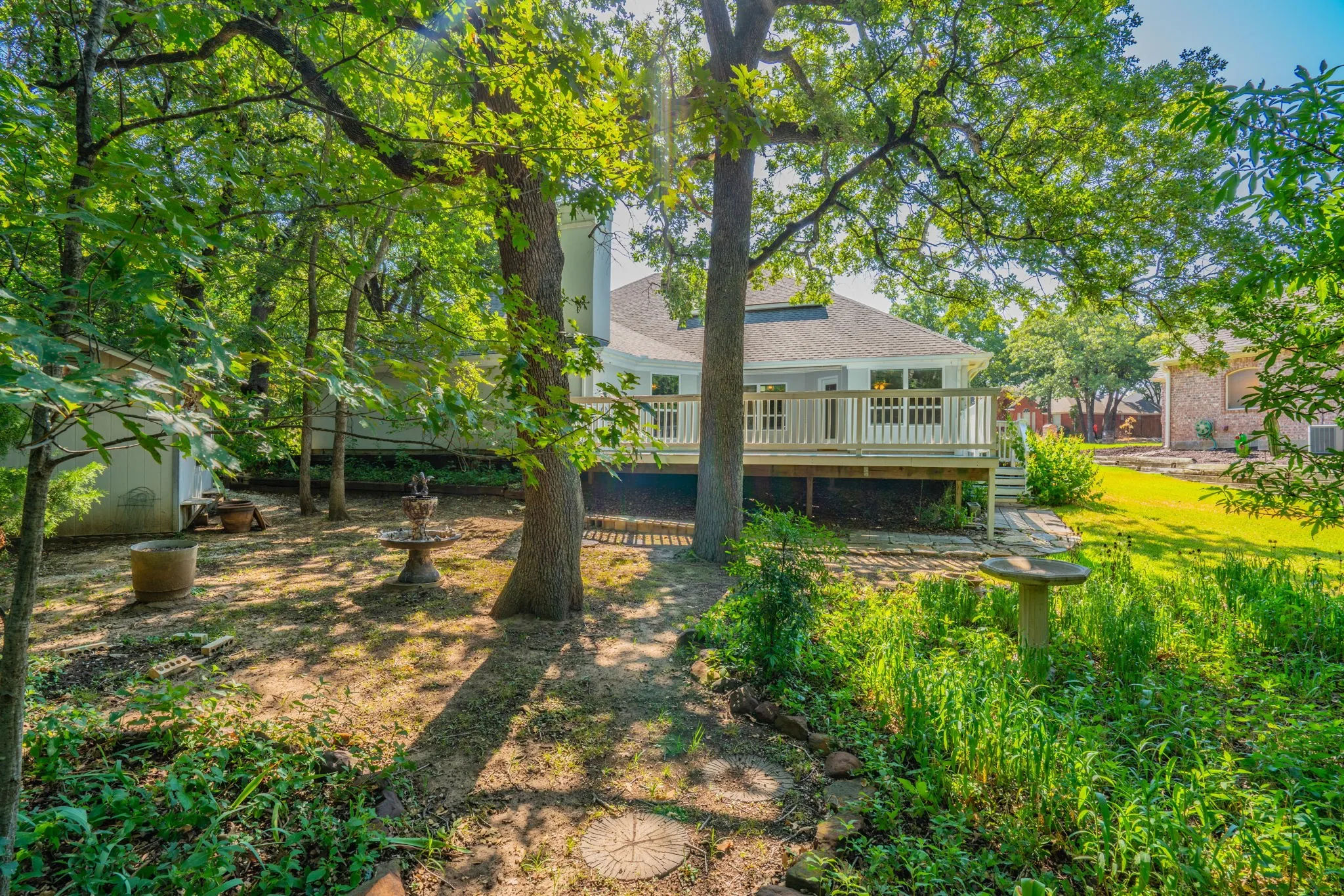 Trees, planting beds, and paths in this shady back yard.