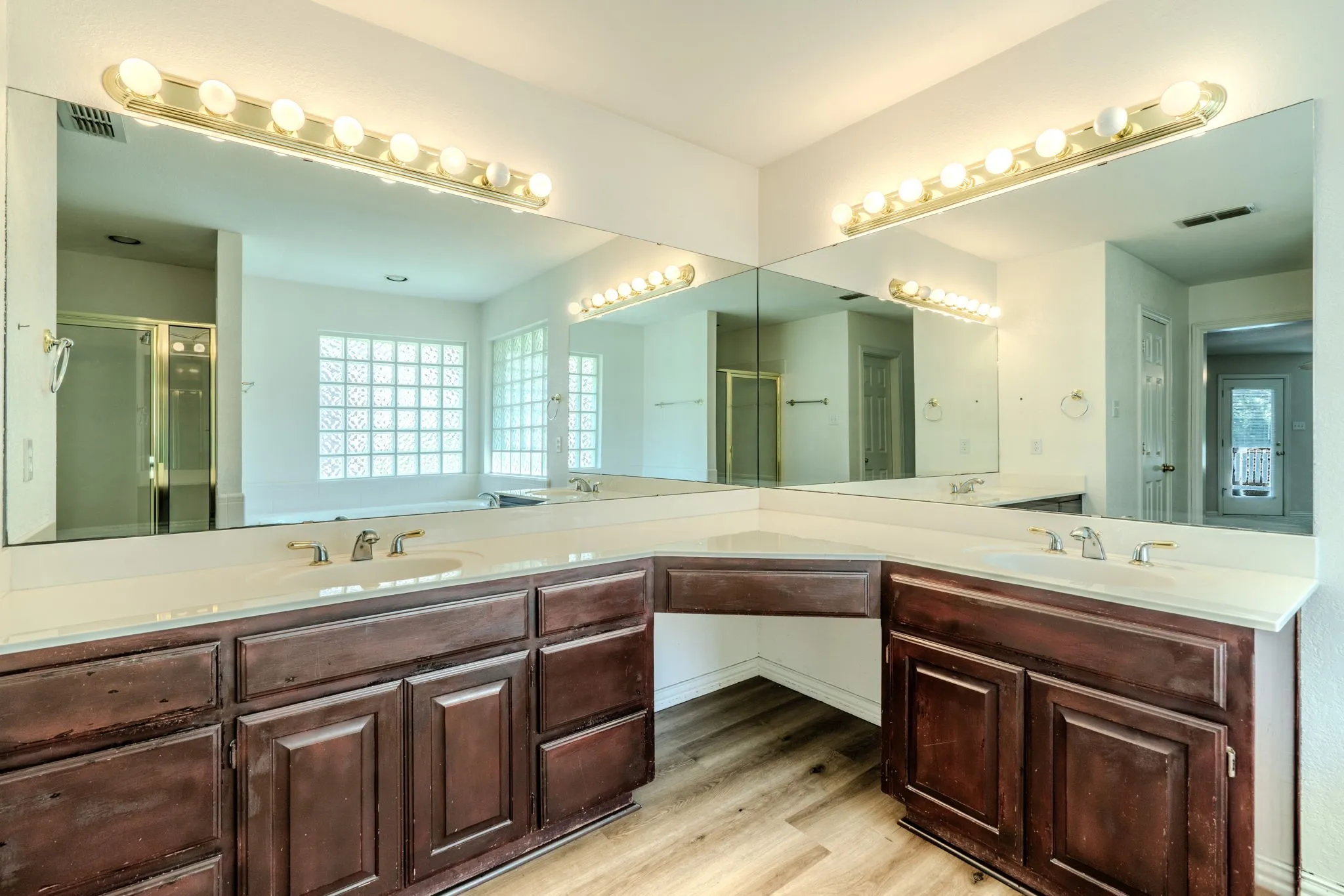 The primary bathroom features separate sinks, a vanity area, separate jetted tub and shower, and new luxury vinyl plank flooring