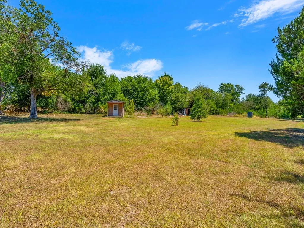 Expansive property featuring a detached shed, mature trees, and natural landscaping