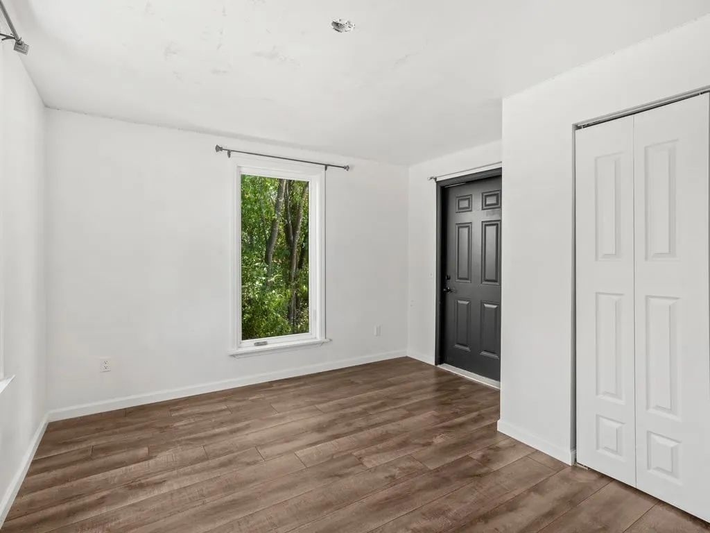 Wood-finish flooring, white walls, and a multi-pane window