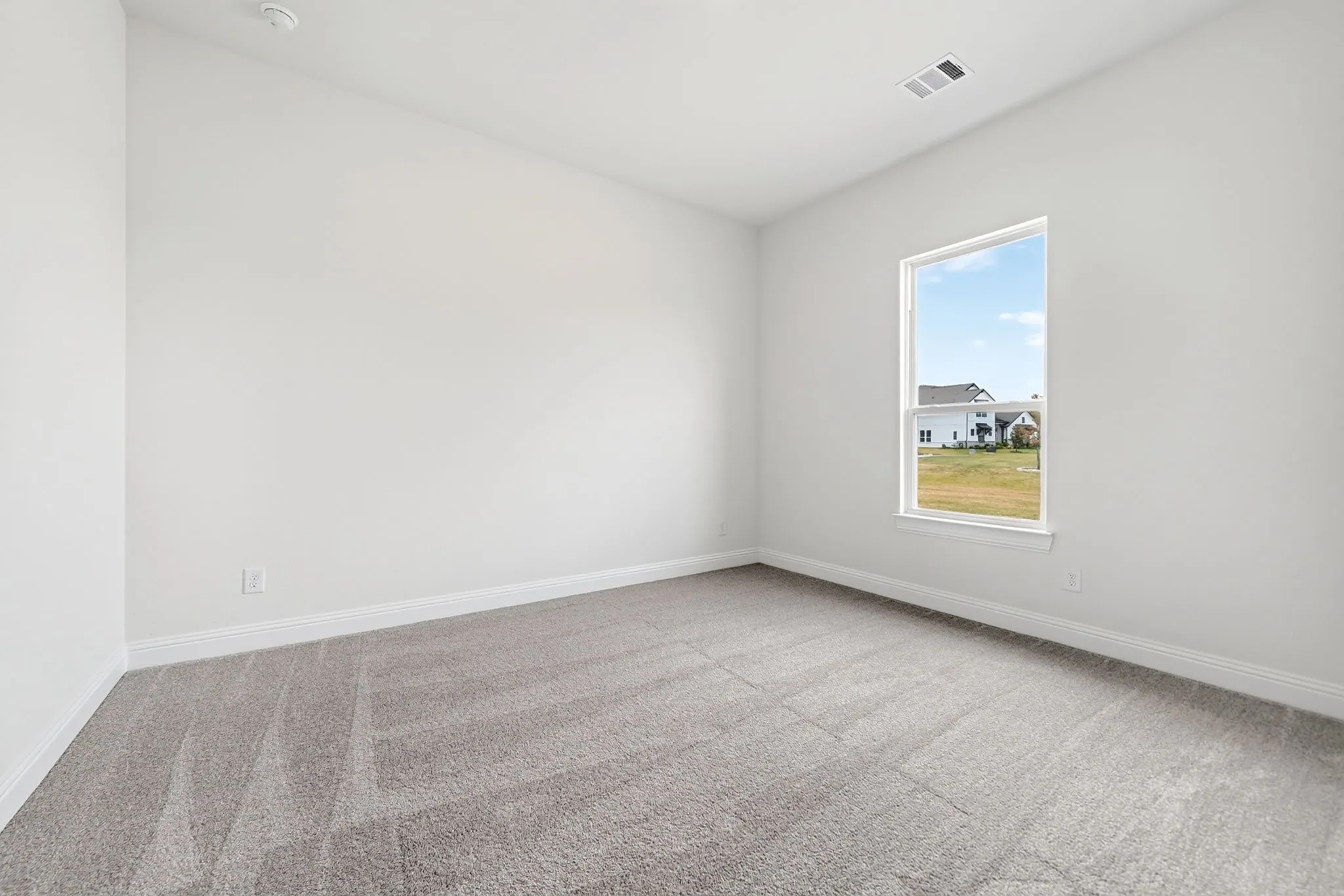 Recessed lighting, wall-to-wall carpeting, and a window with white trim
