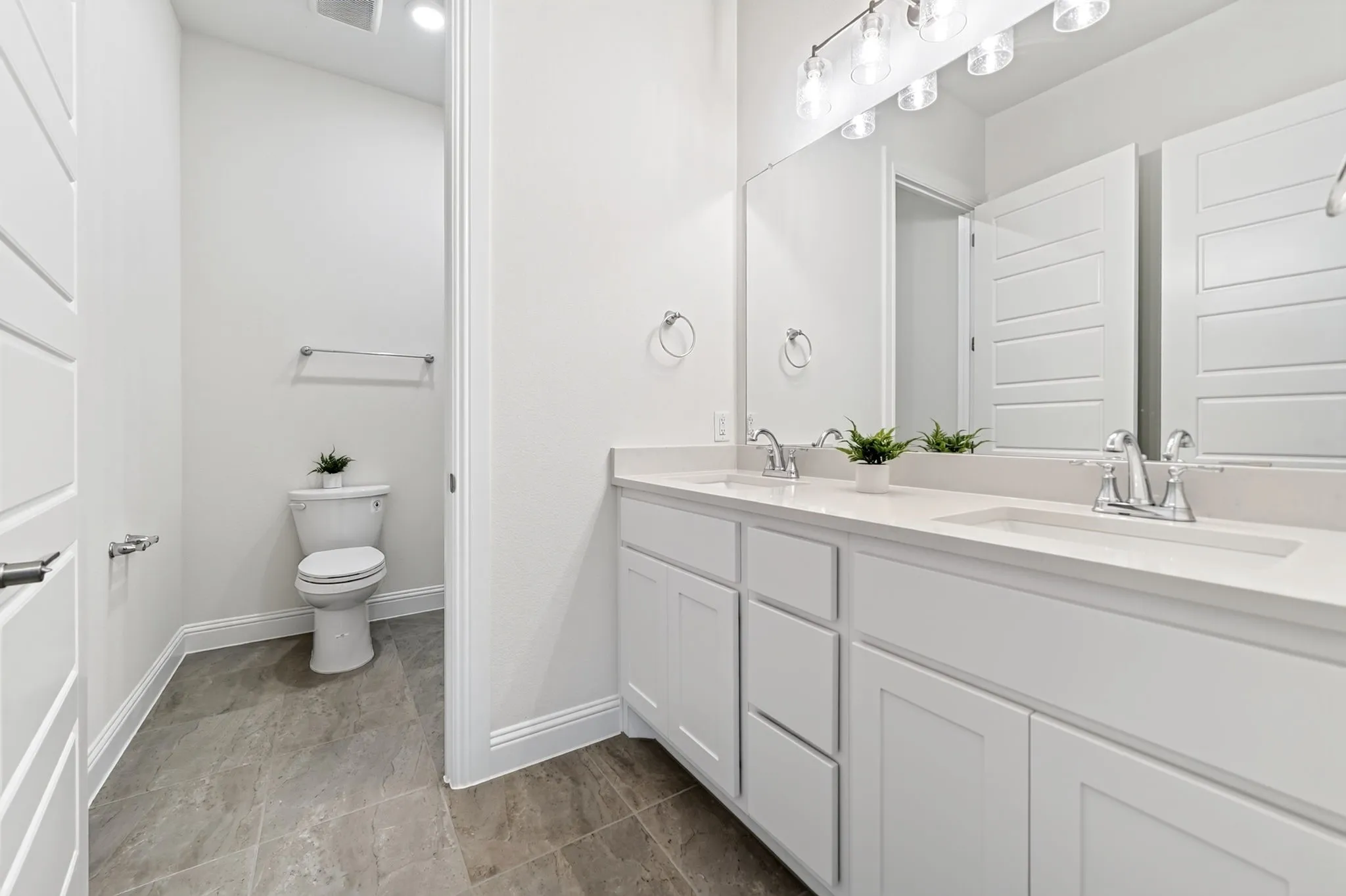 Dual vanity with white cabinetry, light-toned countertops, and chrome fixtures
