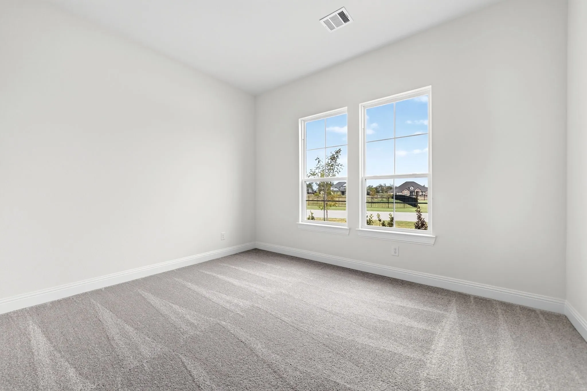 Light-filled interior space with two windows, plush gray carpeting, and clean white walls