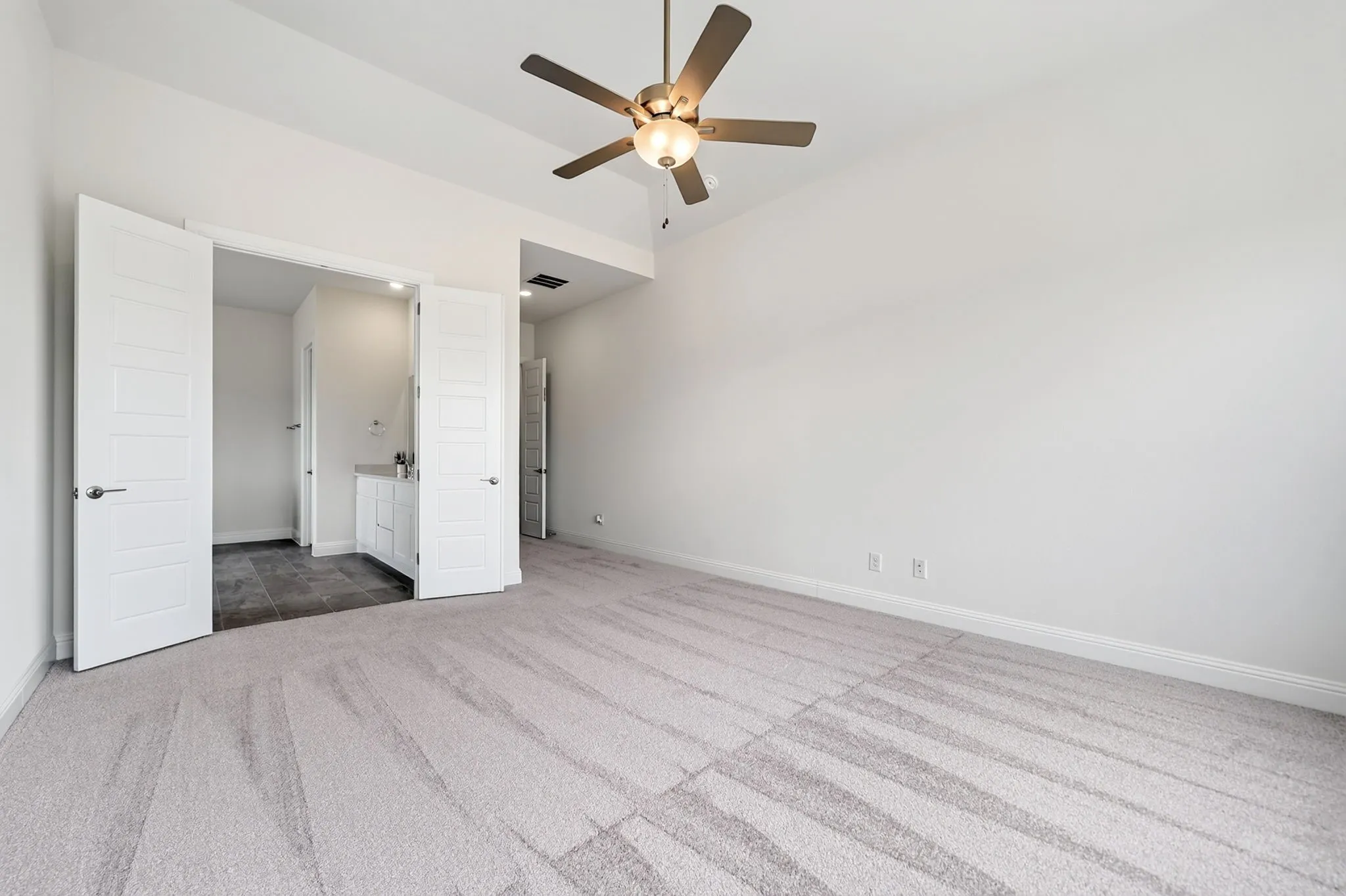 Vaulted ceiling, ceiling fan with integrated lighting, light-toned carpeting, white trim, and white paneled doors