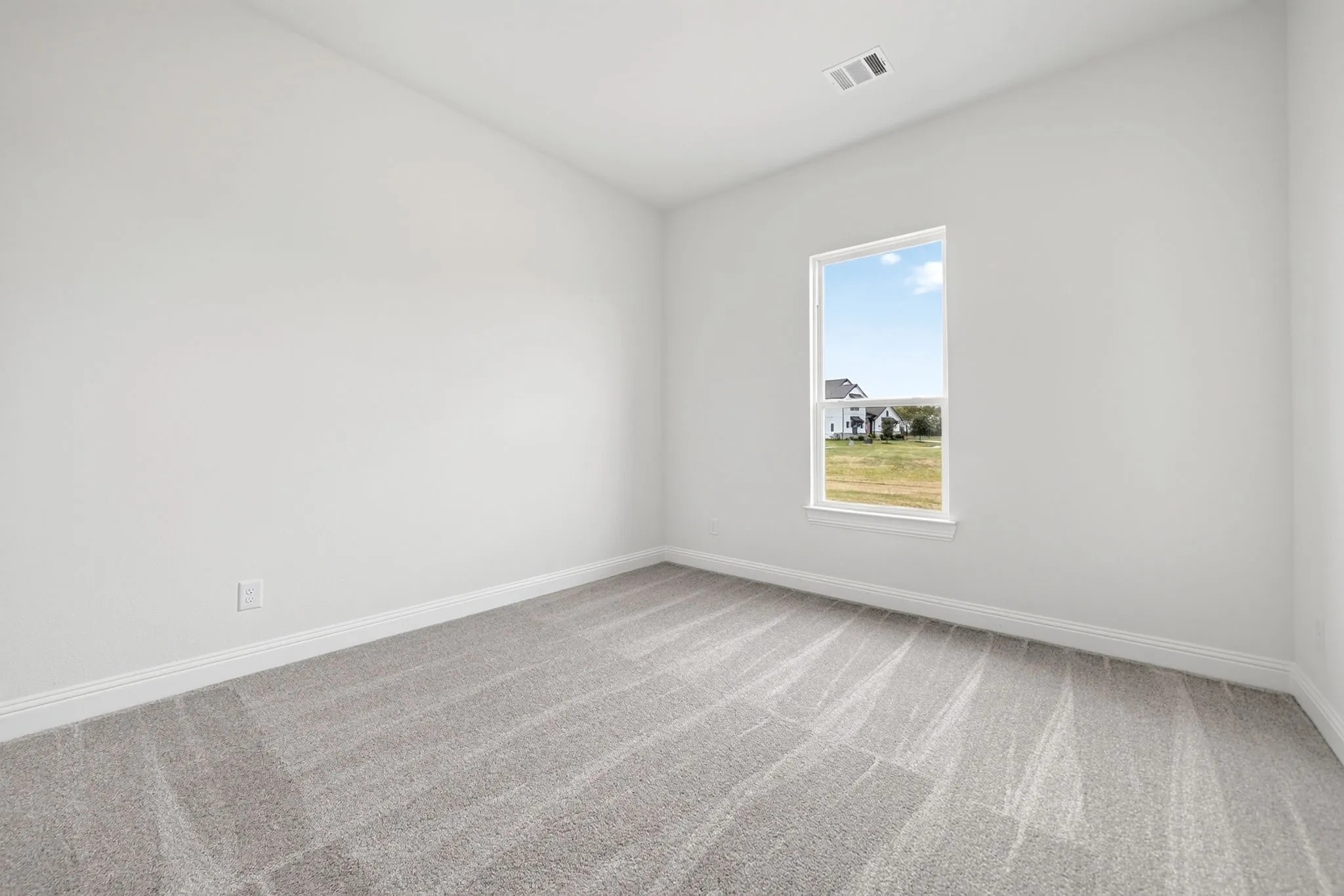 Neutral wall color, window with white trim, gray patterned carpeting, and white baseboards