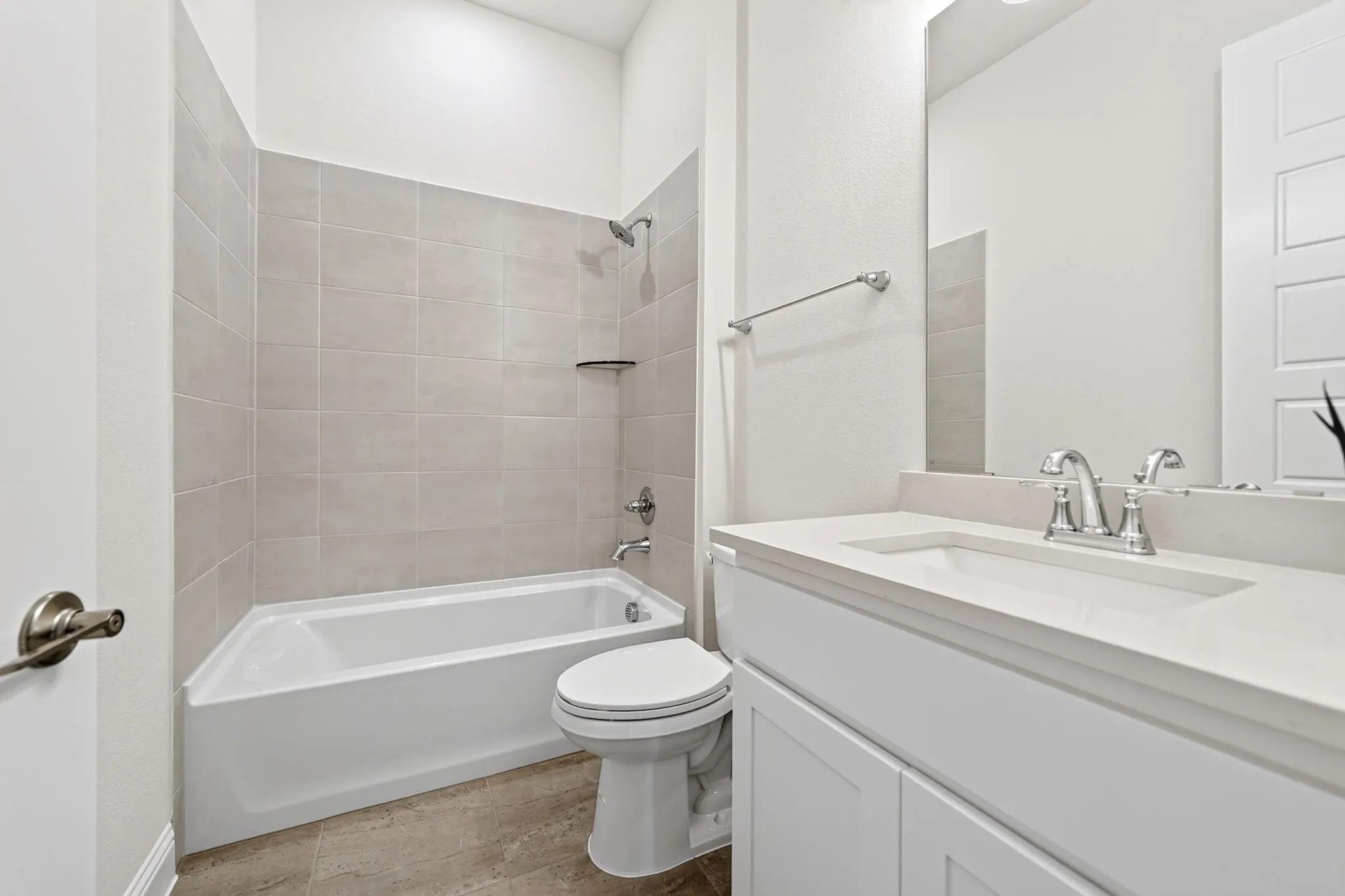 White bathtub with a tile surround, chrome fixtures, and a toilet