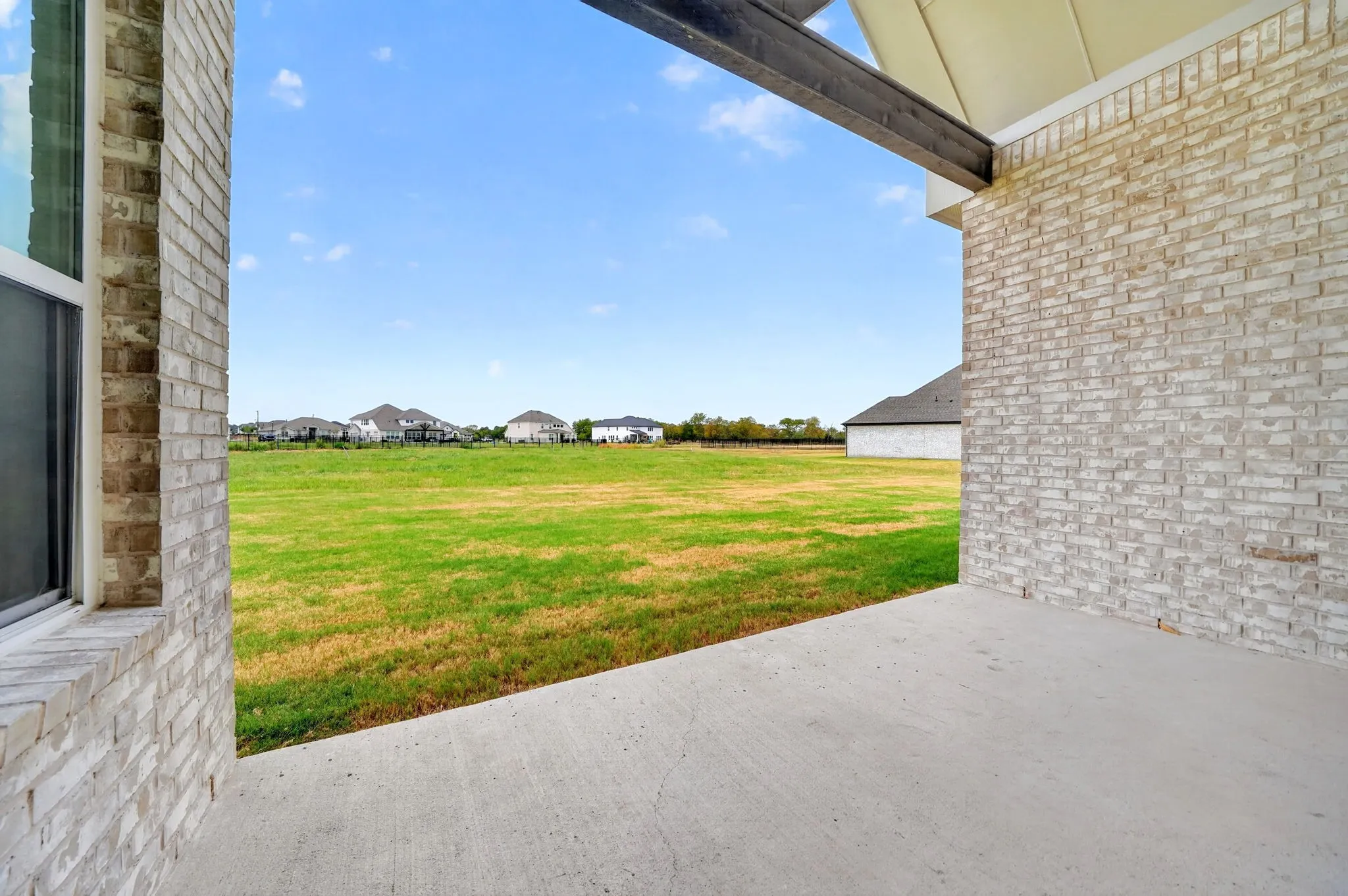 Covered concrete patio with white brick exterior