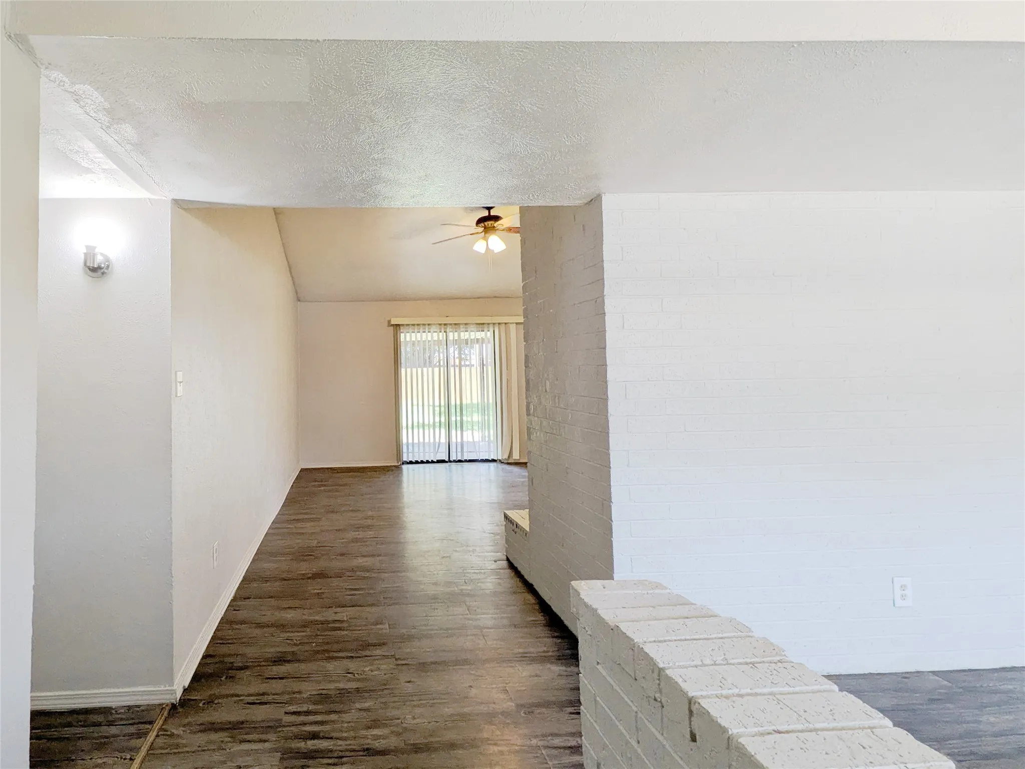 Wood-finish flooring throughout, with a ceiling fan fixture, and sliding glass doors
