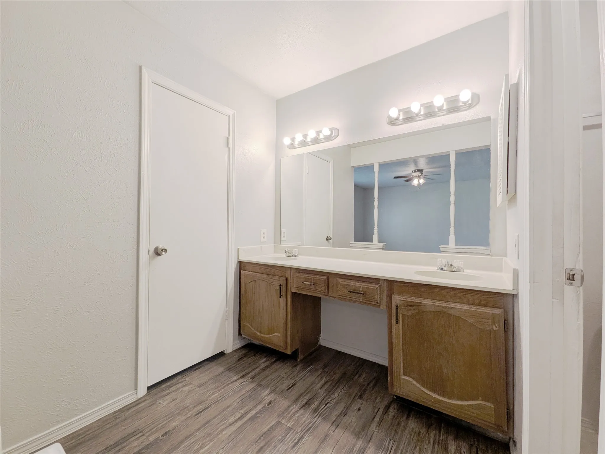 Double vanity with wood-finish cabinetry, integrated sinks, and polished chrome fixtures