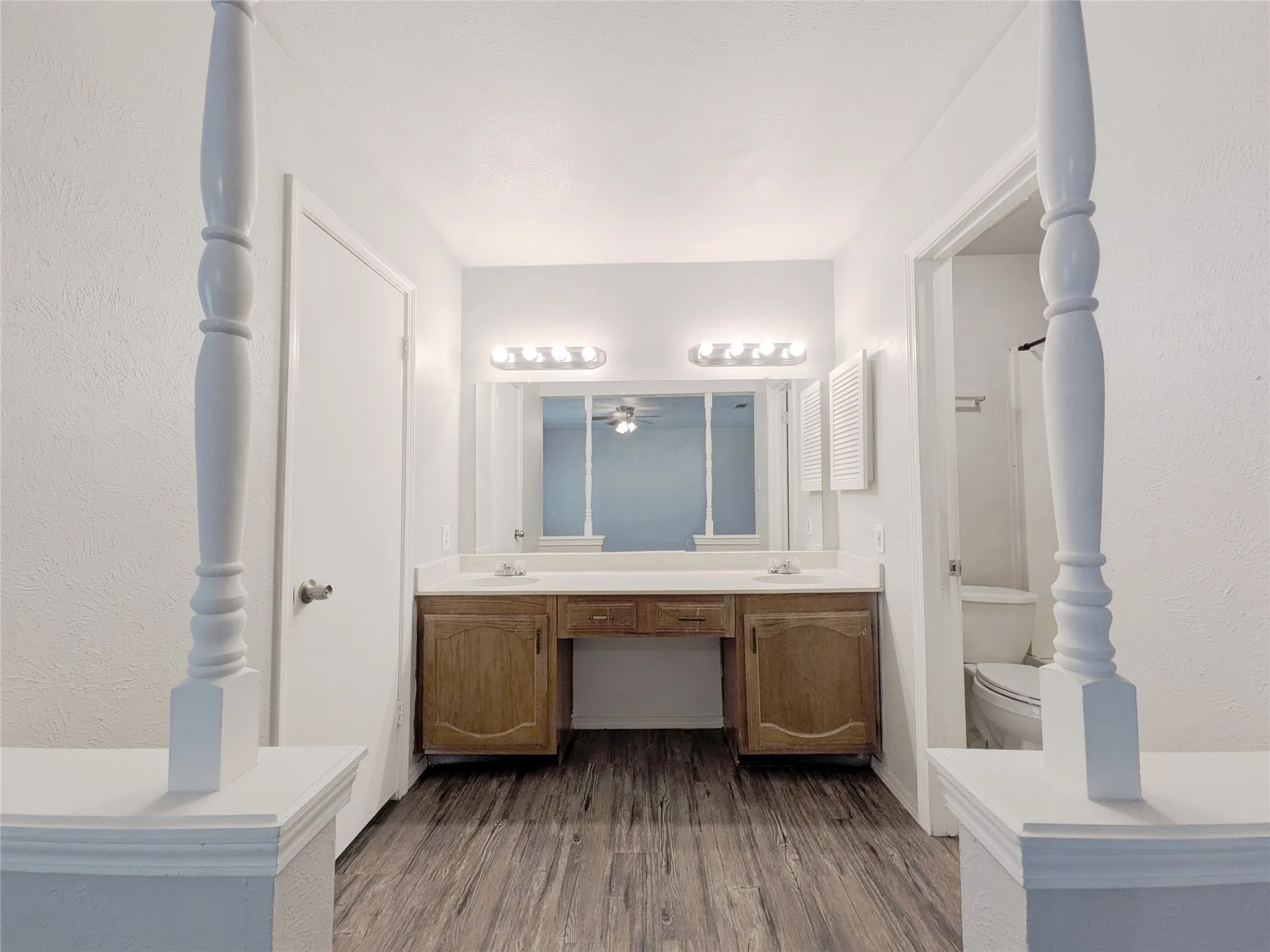 Dual vanity with wood-finish cabinetry, integrated sinks, and polished countertops