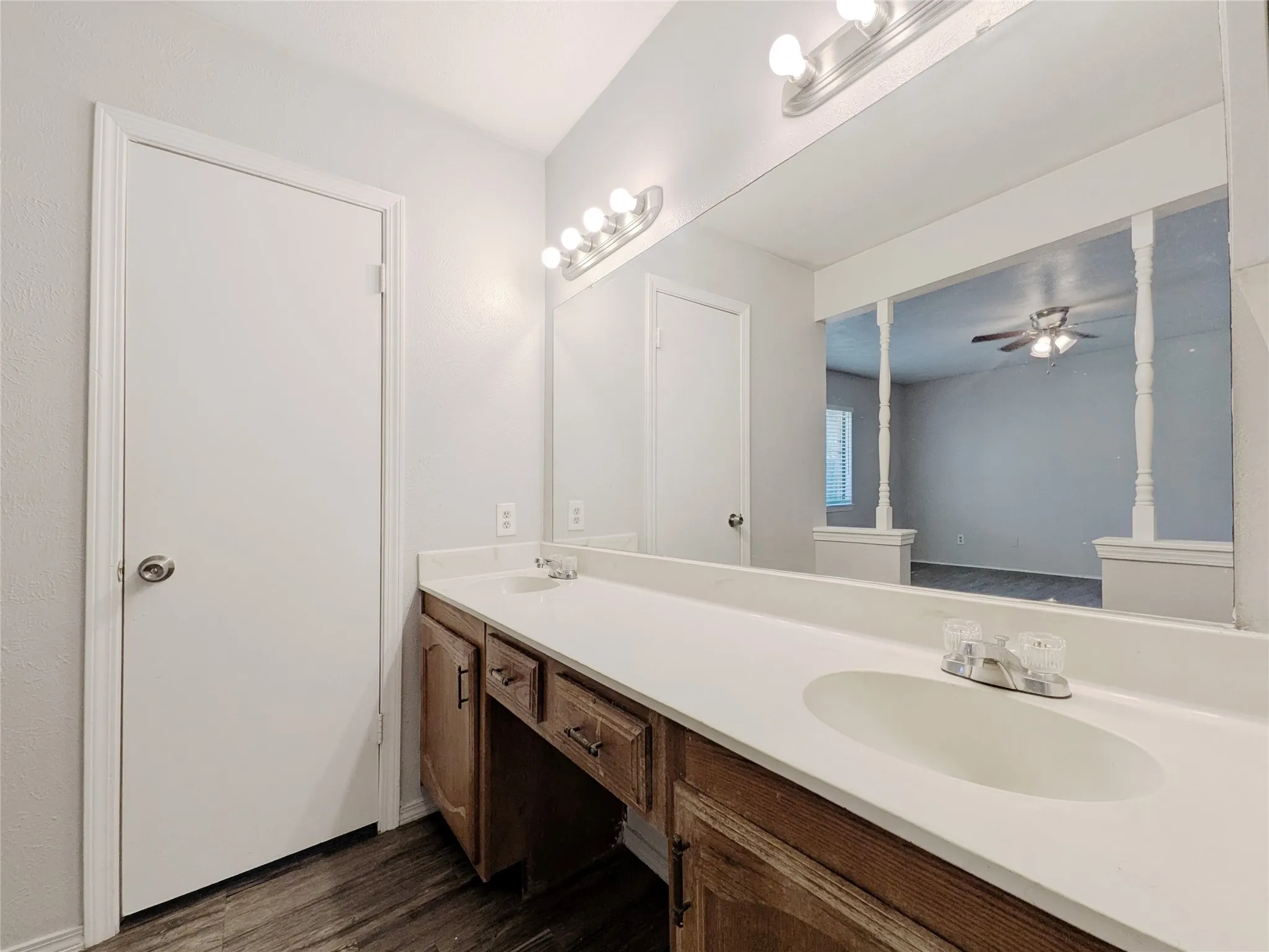 Dual vanity with integrated sinks, ample countertop space, wood-finish cabinetry, and overhead lighting