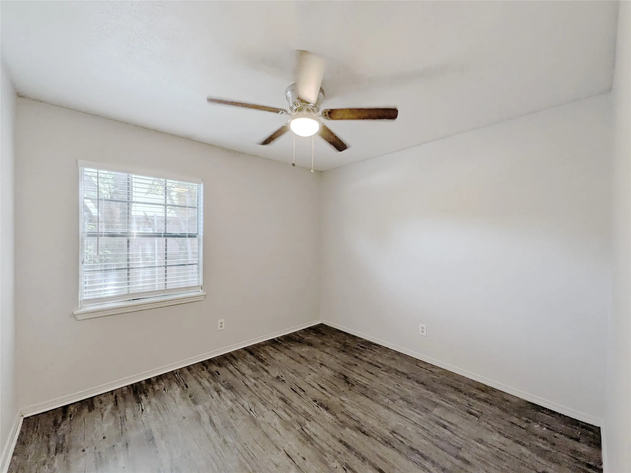 Wood-finish flooring, single window with blinds, ceiling fan with light fixture, and neutral wall paint