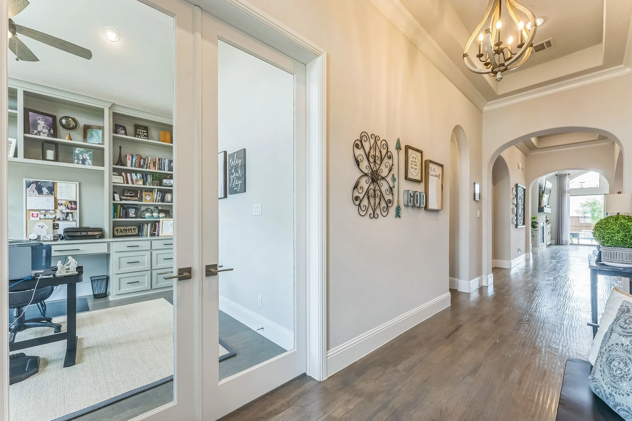 Entryway featuring wood-finish flooring, arched doorways, and a tray ceiling with a chandelier