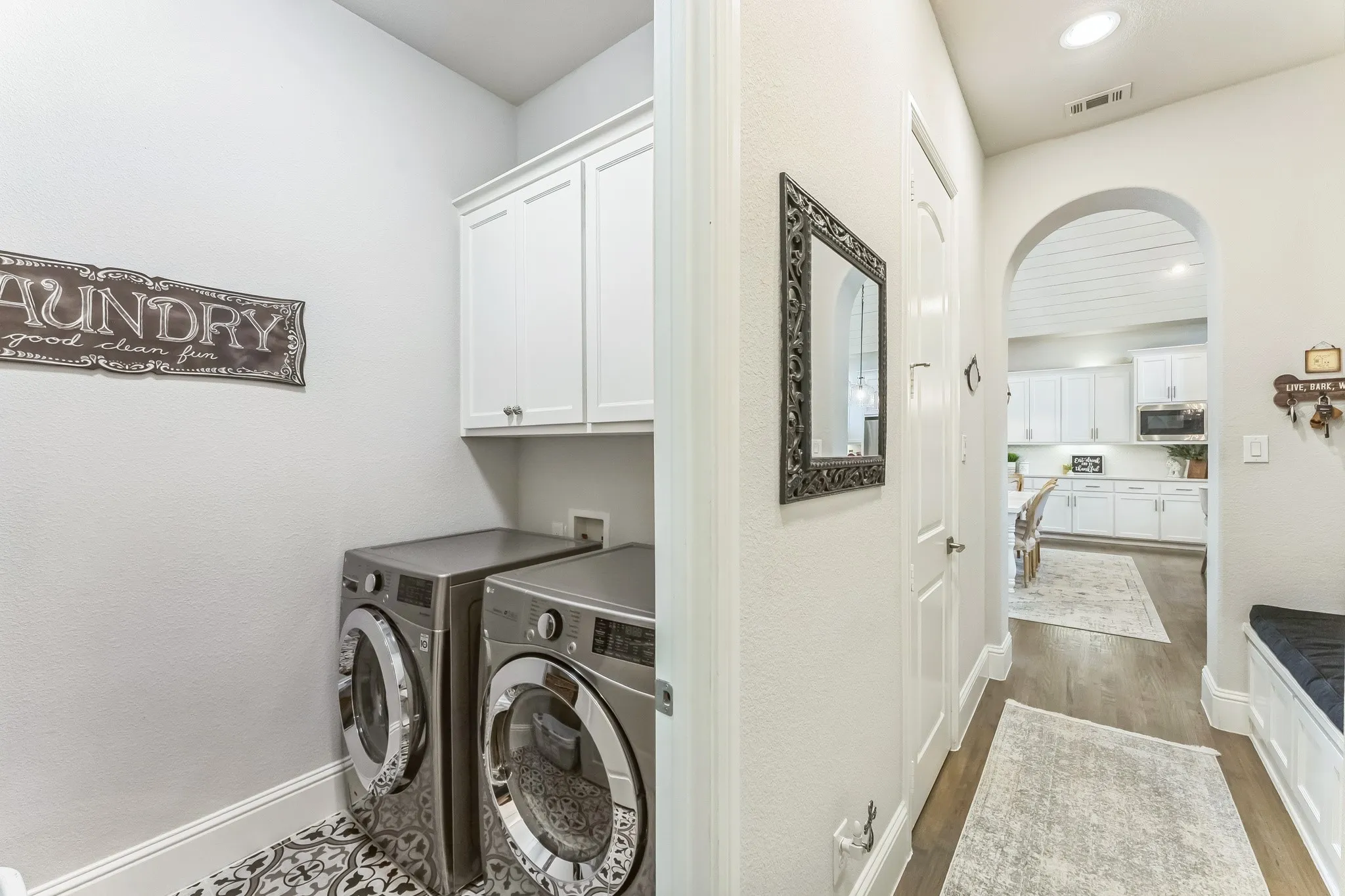 Dedicated laundry area with patterned floor tile and white cabinetry