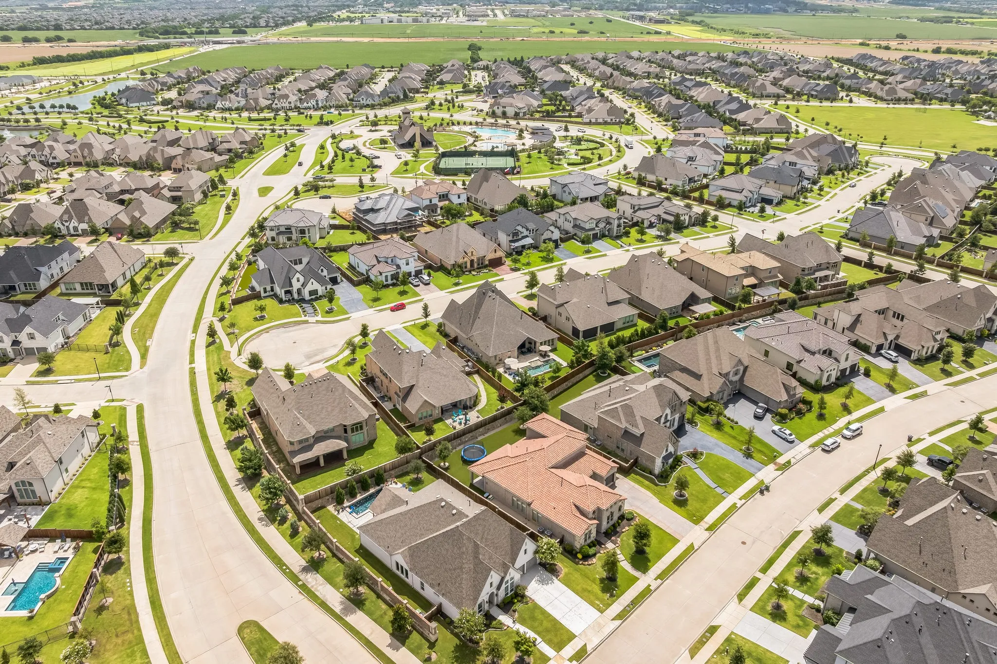 Expansive residential community with manicured landscaping, wide paved streets, and numerous properties featuring private swimming pools