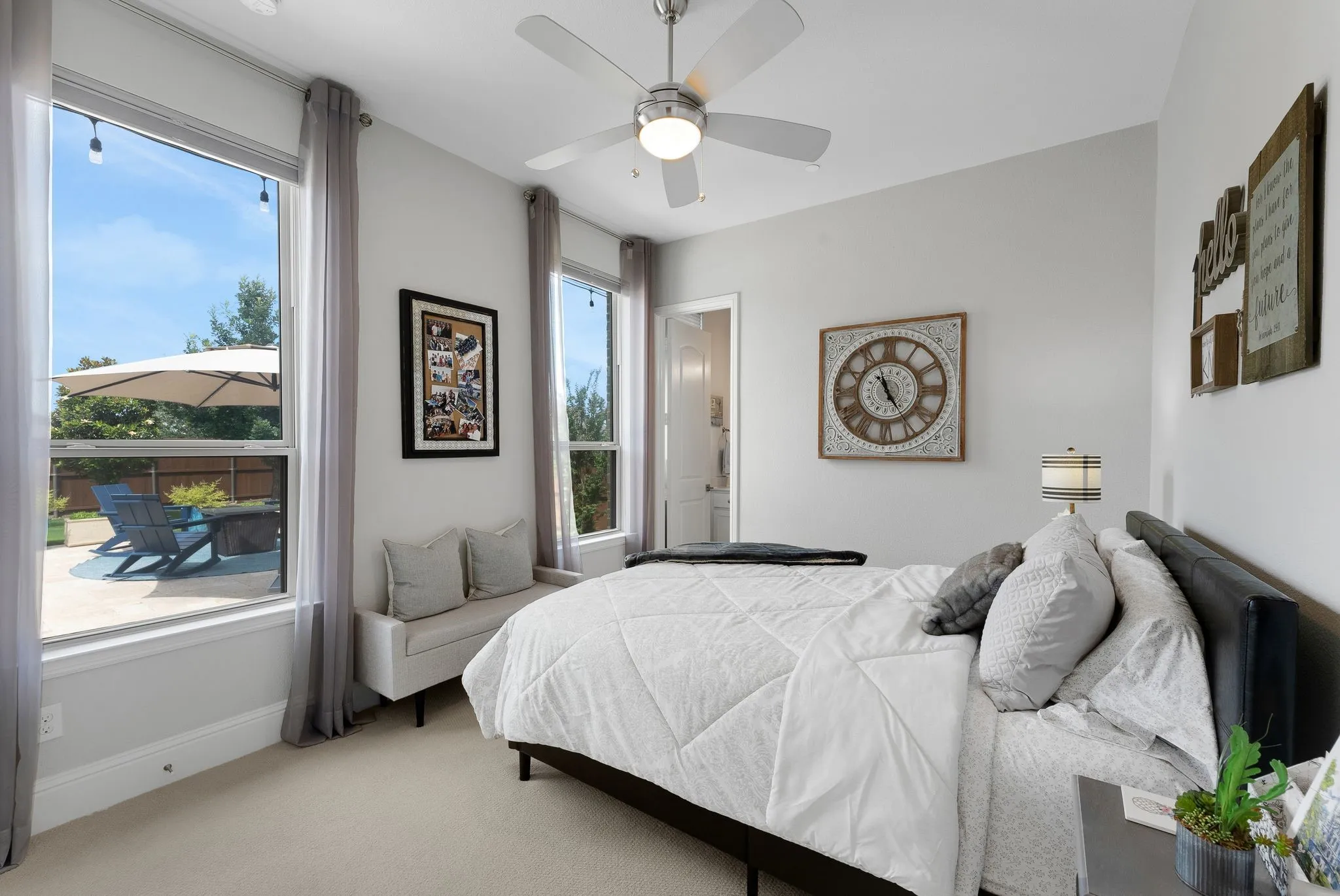 Carpeted bedroom featuring multiple large windows, a ceiling fan with light, and light-colored walls