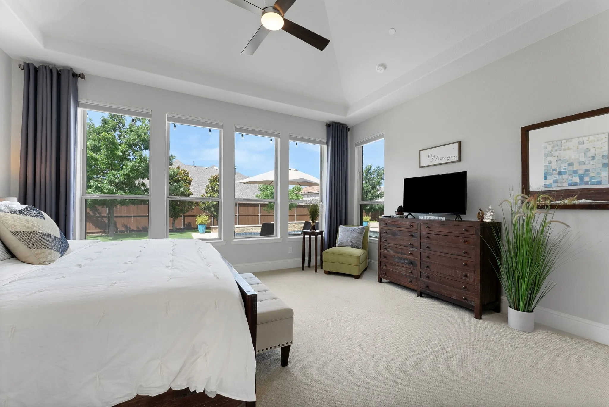 Tray ceiling with recessed lighting, ceiling fan, multiple large windows, light neutral wall color, and light-toned carpet