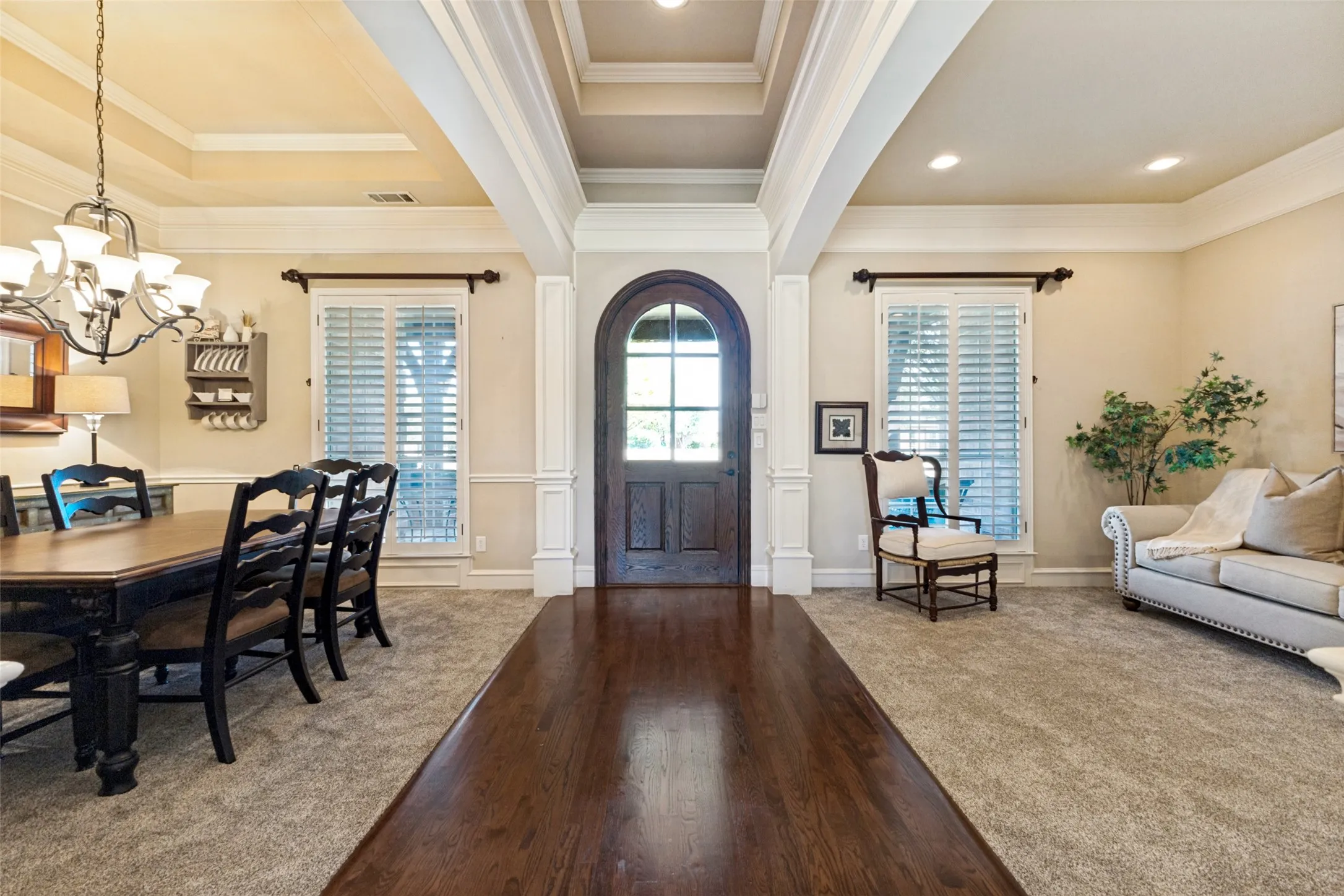 Elegant entrance with an arched wooden front door, tray ceilings, and extensive crown molding.