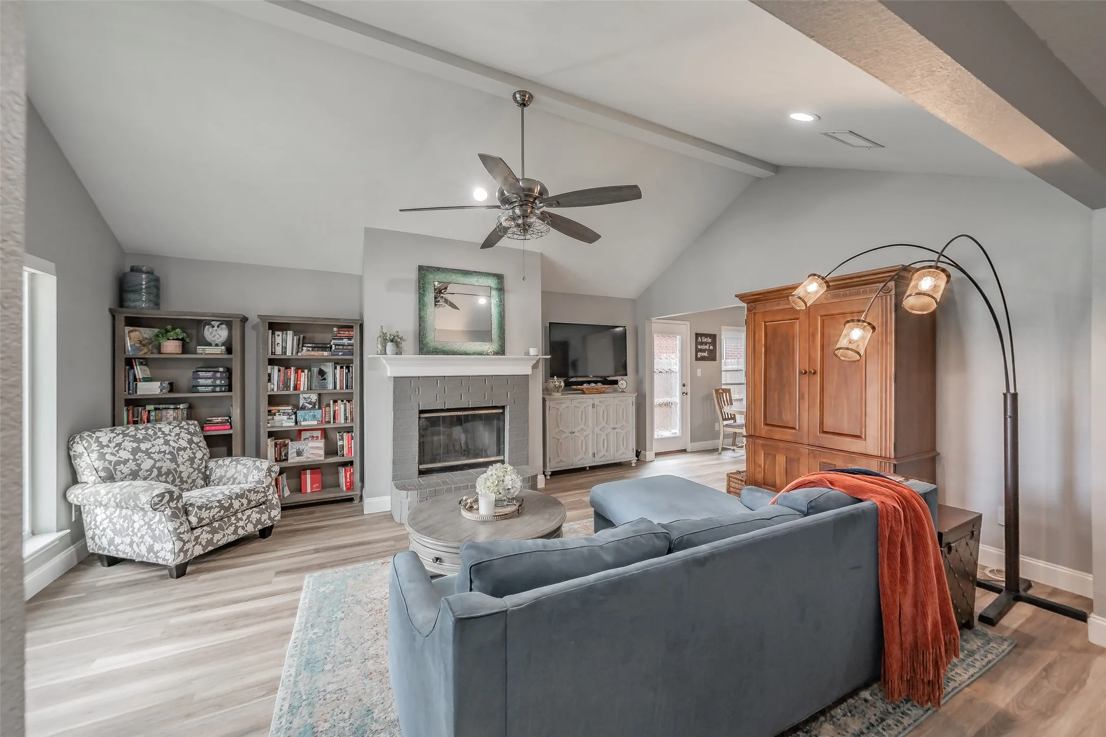 Vaulted ceiling with exposed beams, wood-finish flooring, recessed lighting, and a fireplace with a mantel