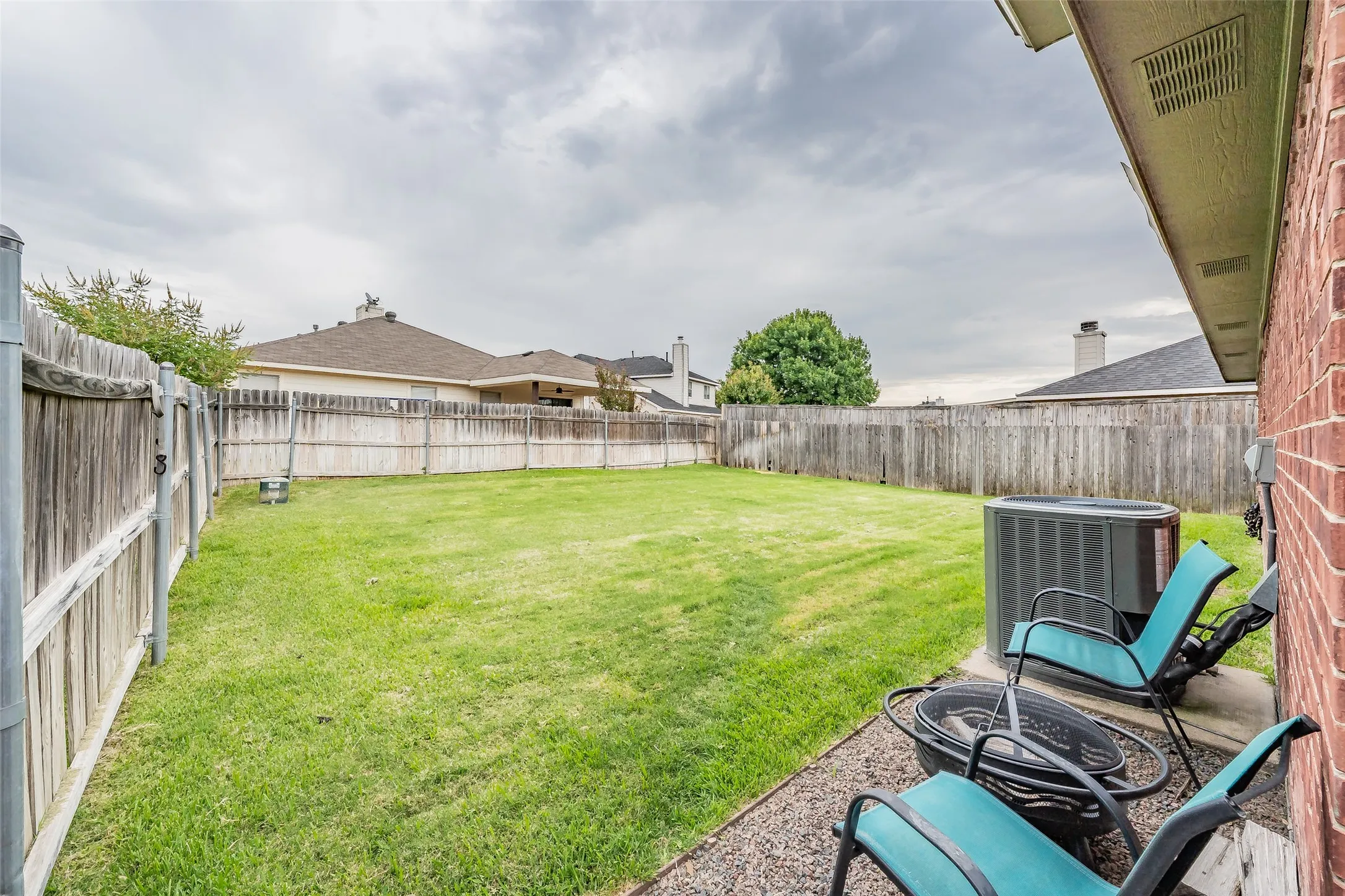 Expansive grassy backyard with perimeter fencing and a dedicated gravel patio area