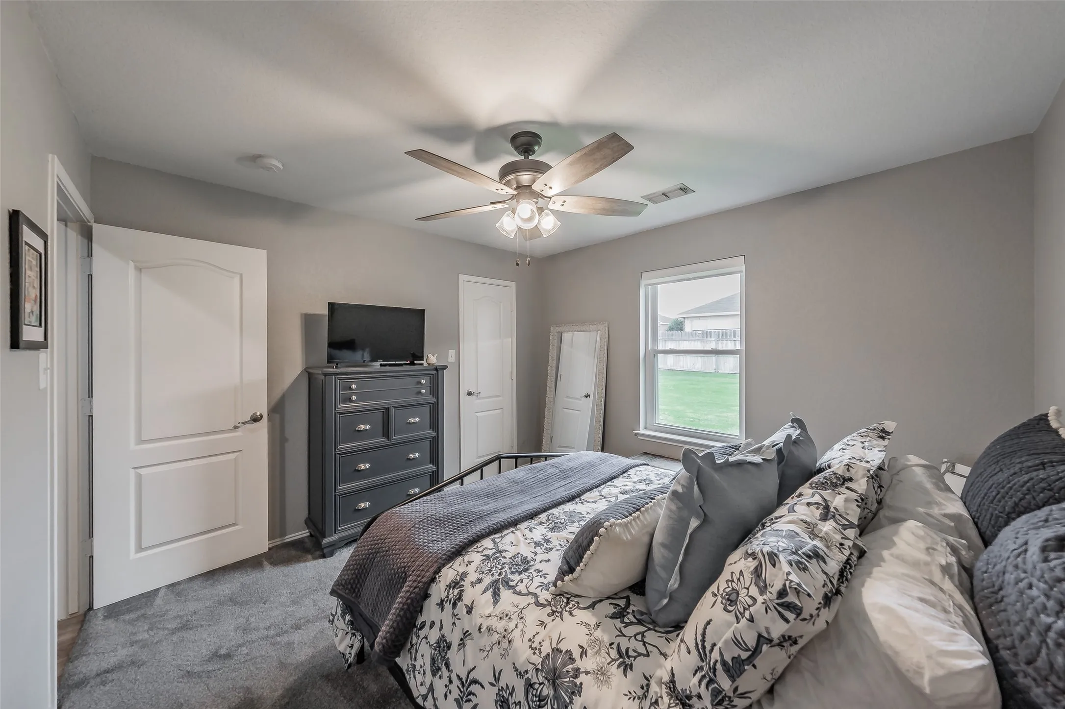 Neutral wall tones, gray carpeting, white trim, and a ceiling fan with integrated lighting