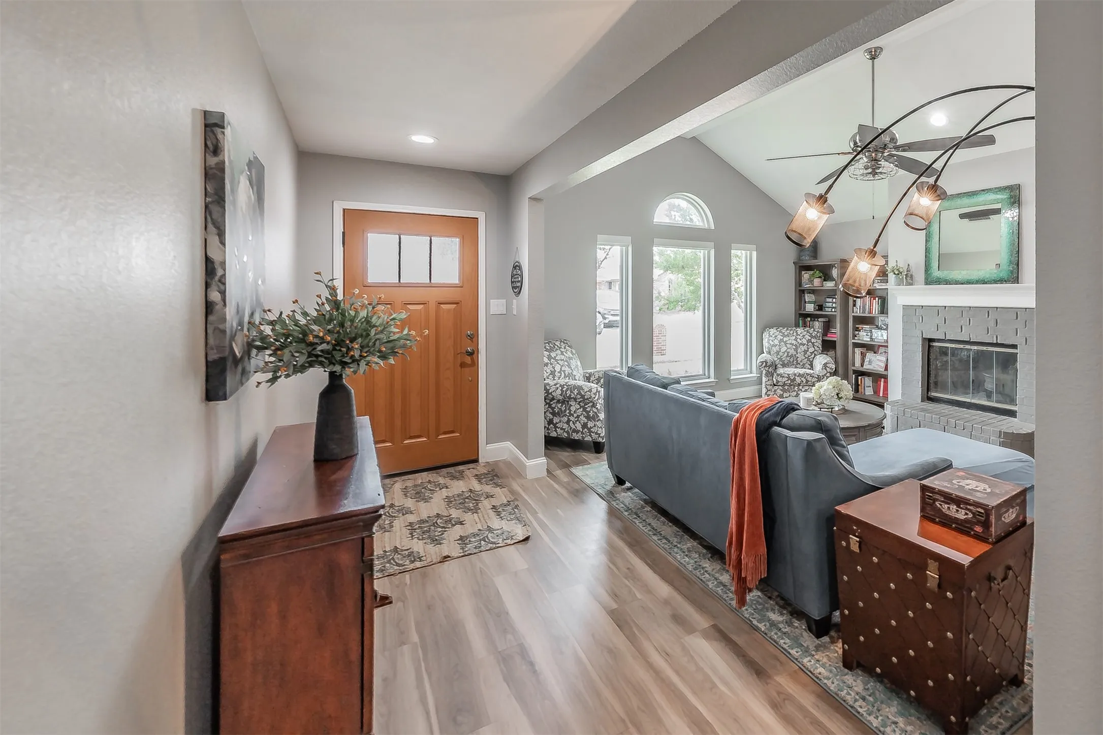 Wood-finish flooring throughout, featuring a vaulted ceiling and an arched window