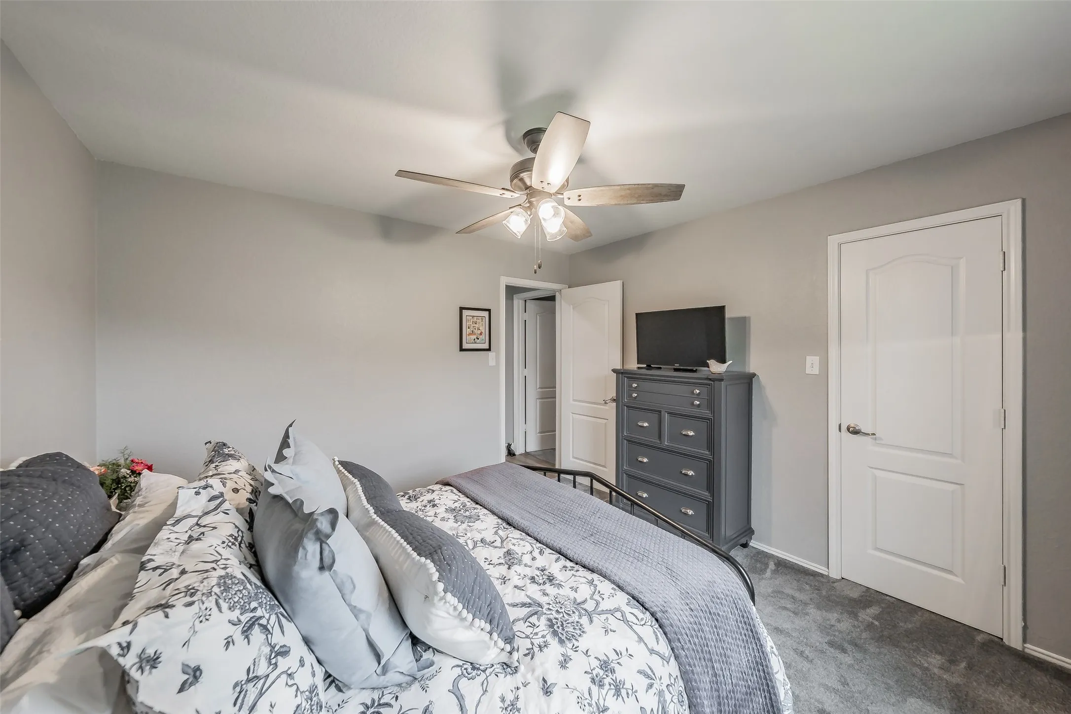 Neutral wall paint, ceiling fan with light fixture, white interior doors, and carpeted flooring
