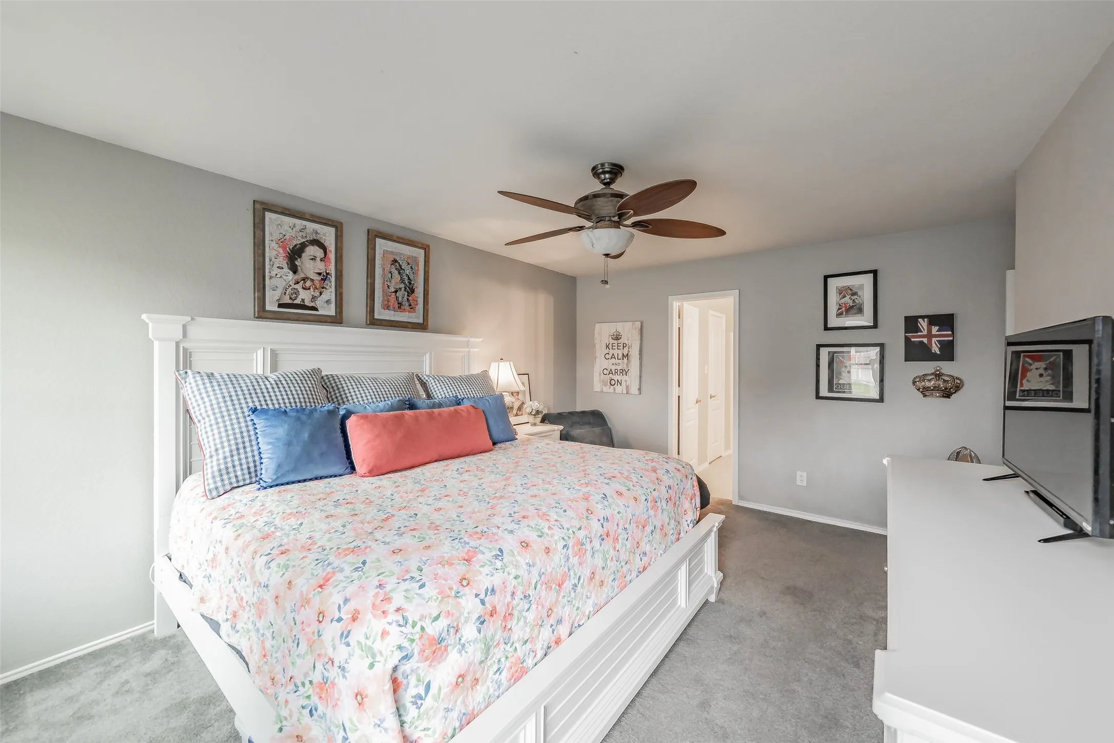 Gray wall paint, ceiling fan with integrated lighting, gray carpet flooring, white painted trim, and a white interior door