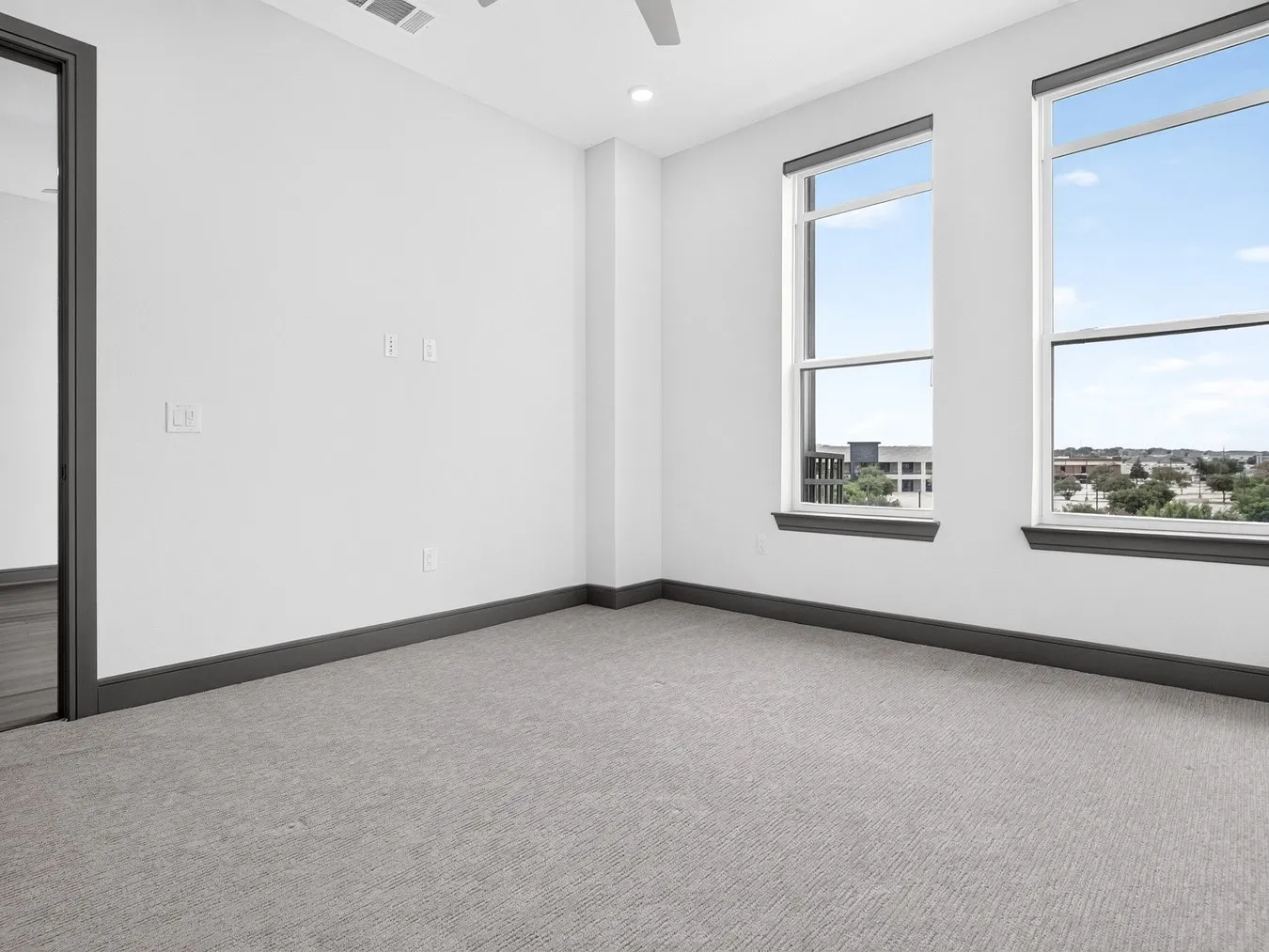Two large windows, gray carpet, dark trim, recessed lighting, and a ceiling fan