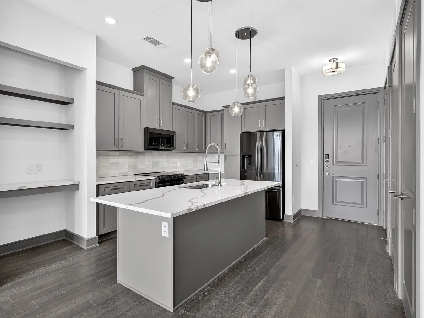 Kitchen featuring a center island with a stone-finish countertop, gray cabinetry, stainless steel appliances, and wood-finish flooring