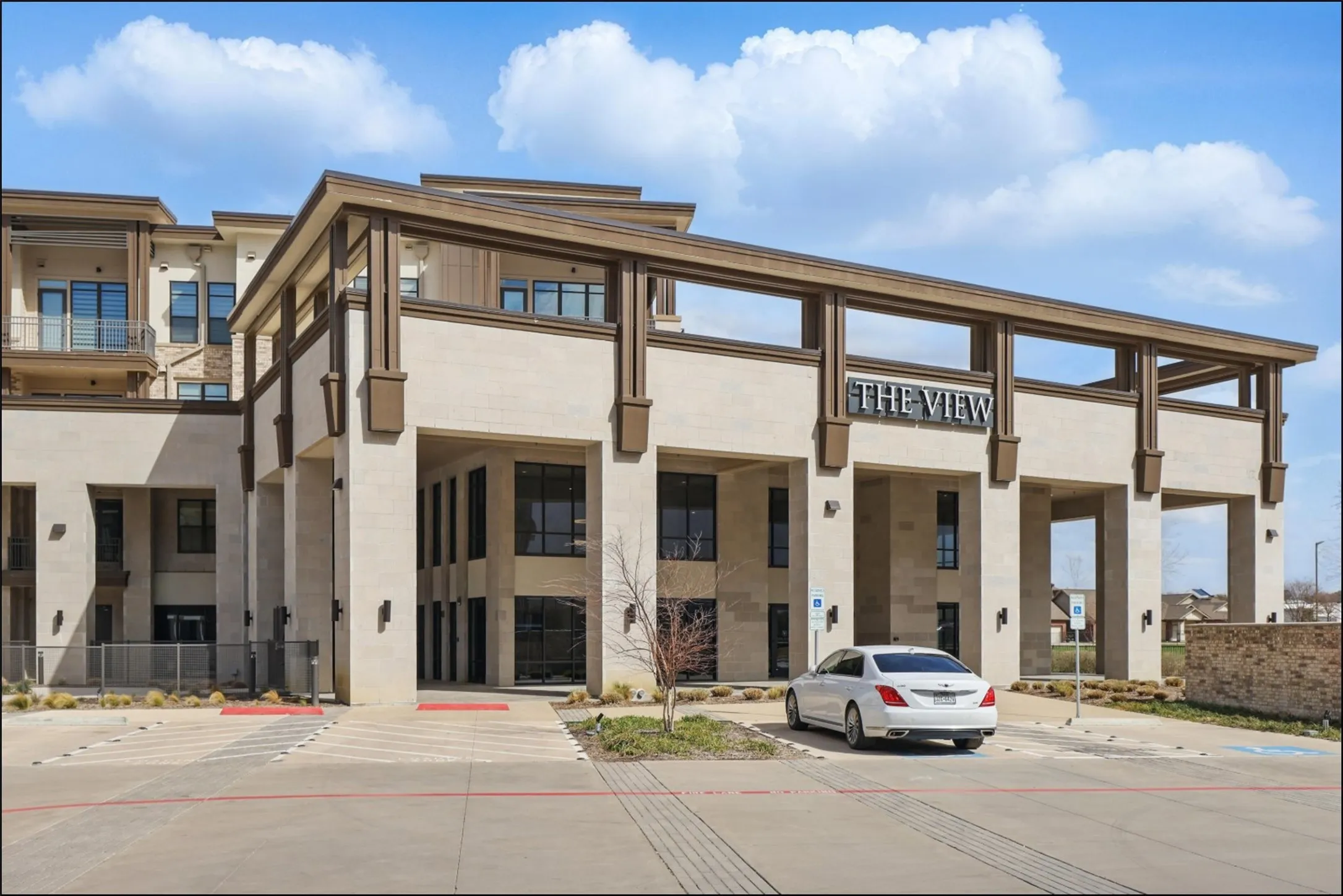 Modern architecture featuring a stone and stucco exterior, prominent entryway with columns, and upper-level balconies